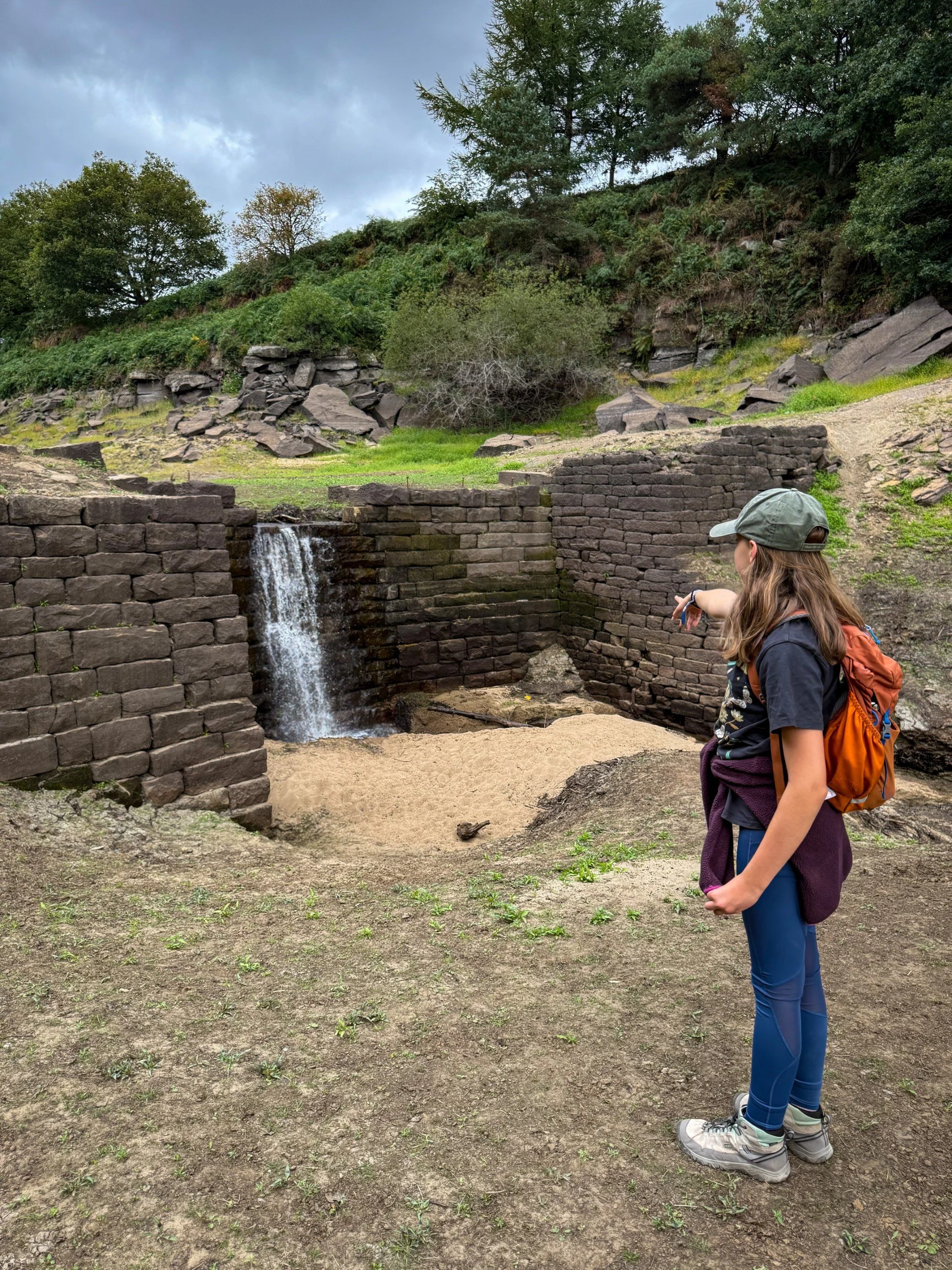 Child pointing at a waterfall over a ruined wall