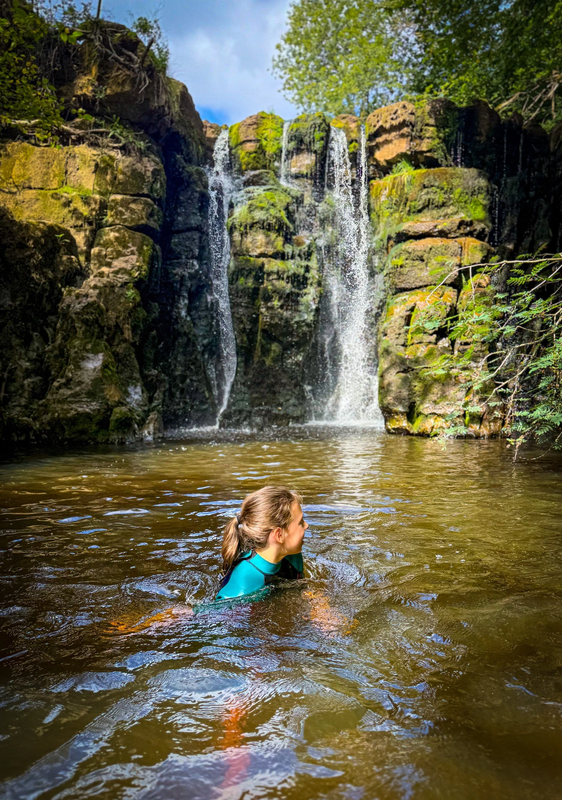 Child swimming in the waterfalls in Keld