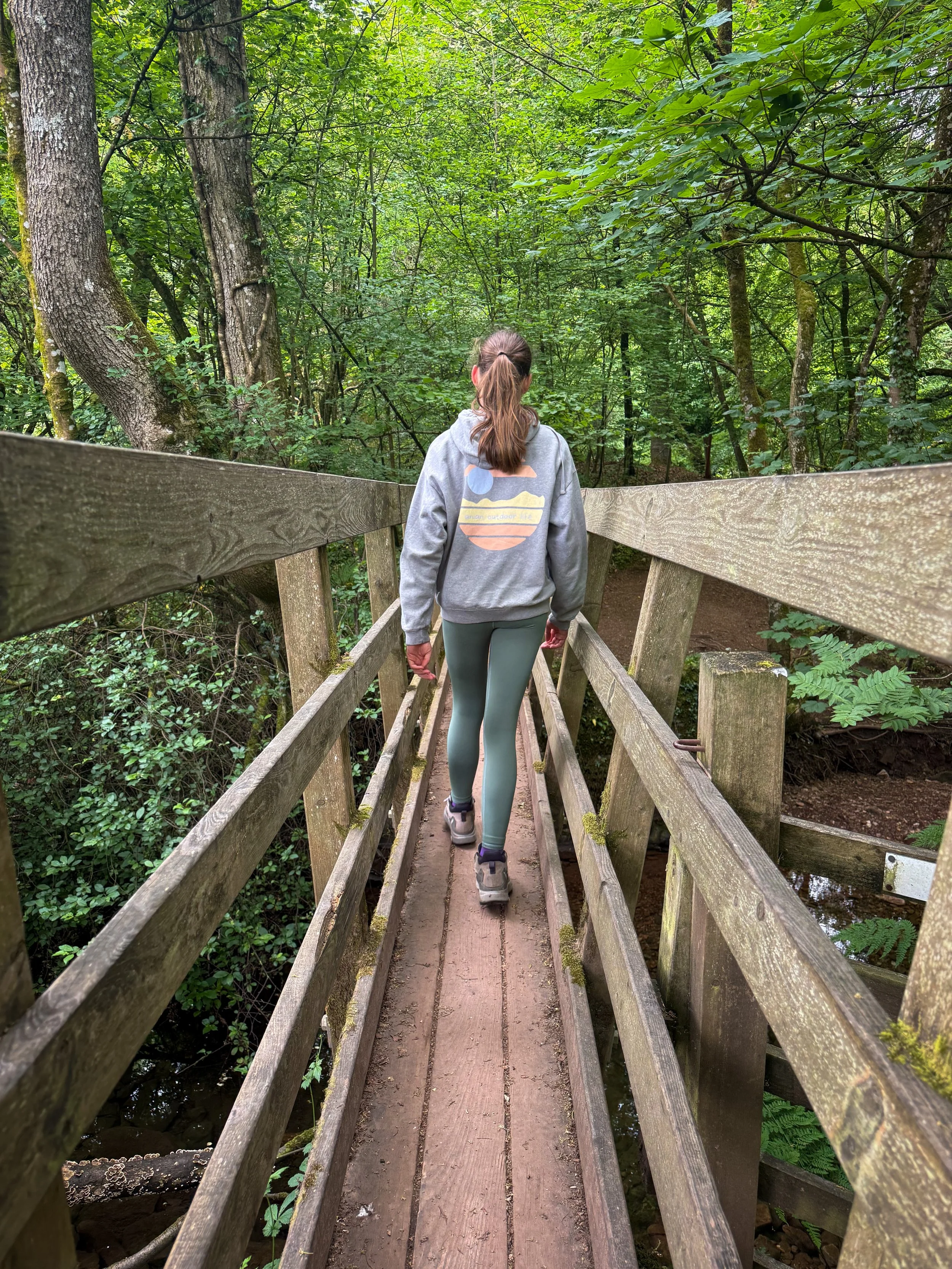 Child walking across a wooden footbridge into woods