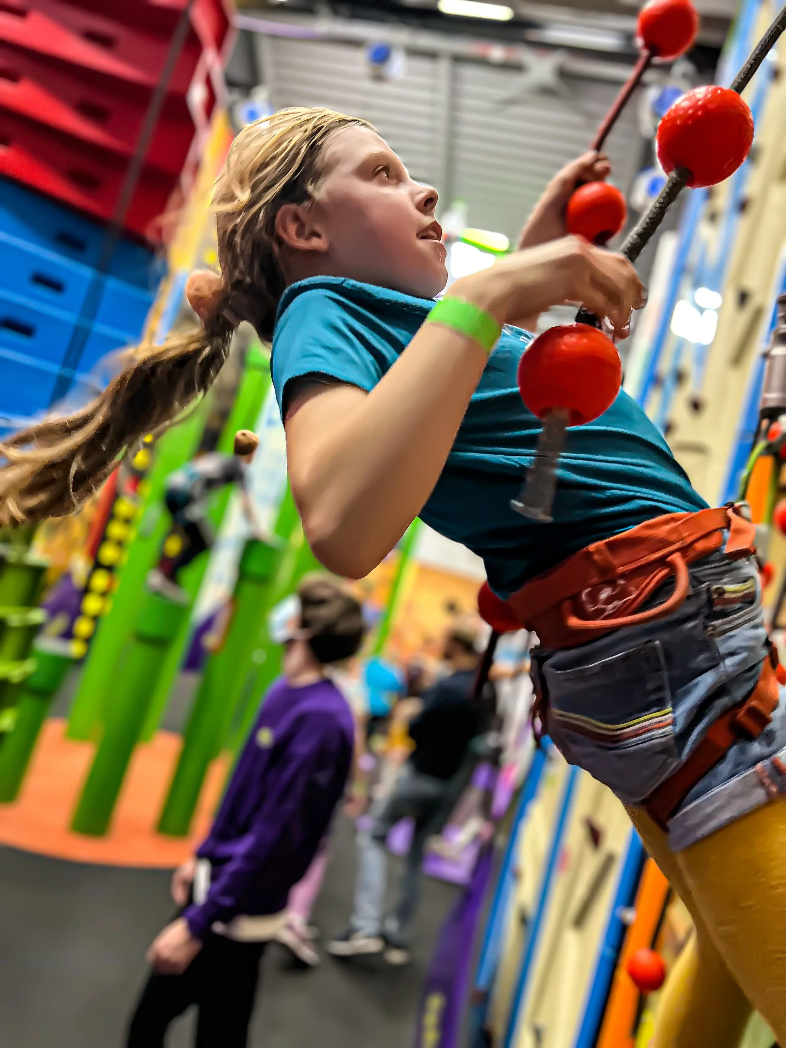 Child climbing up a fun indoor climbing wall with ropes