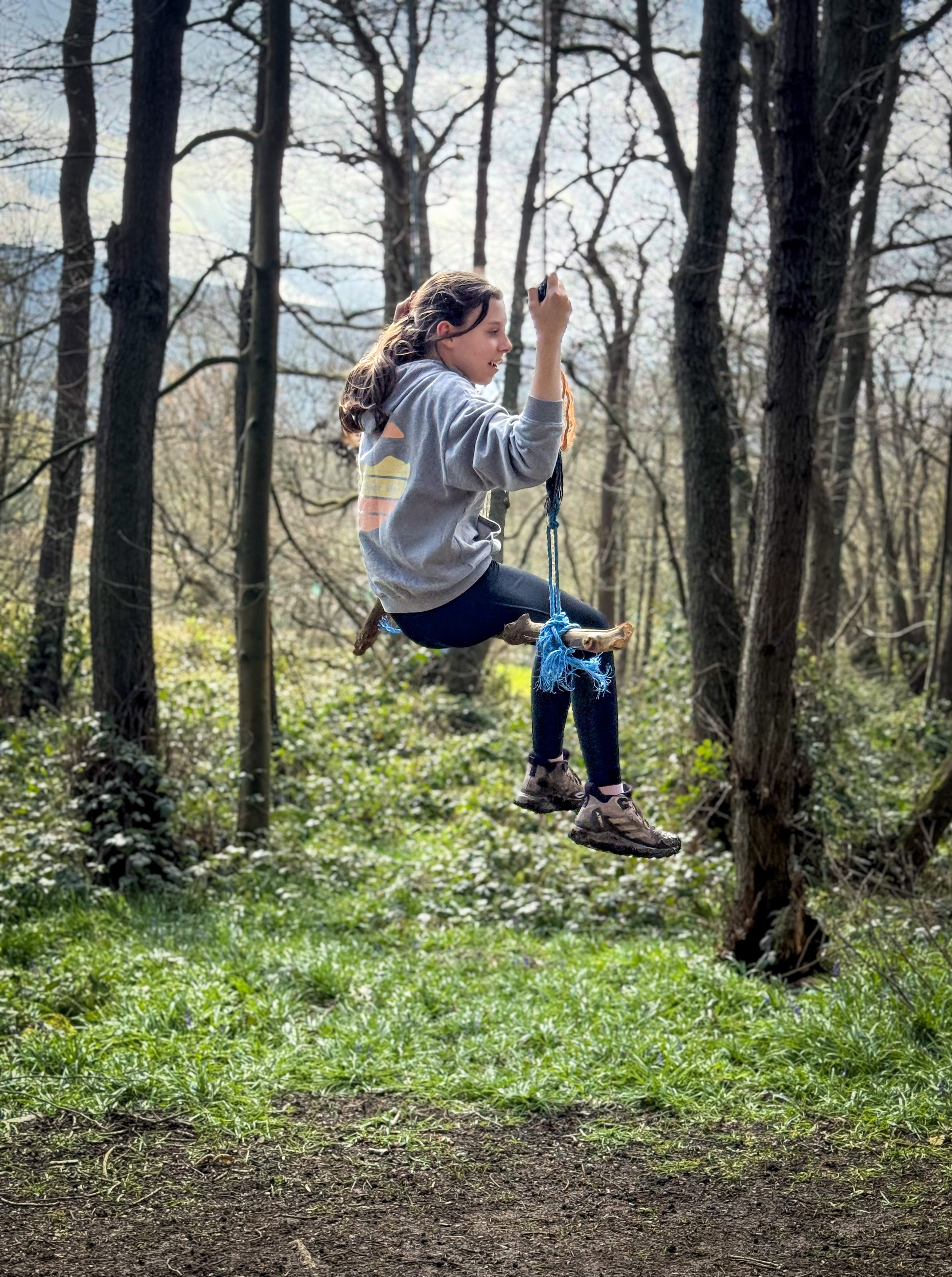 Child on rope swing in the woods
