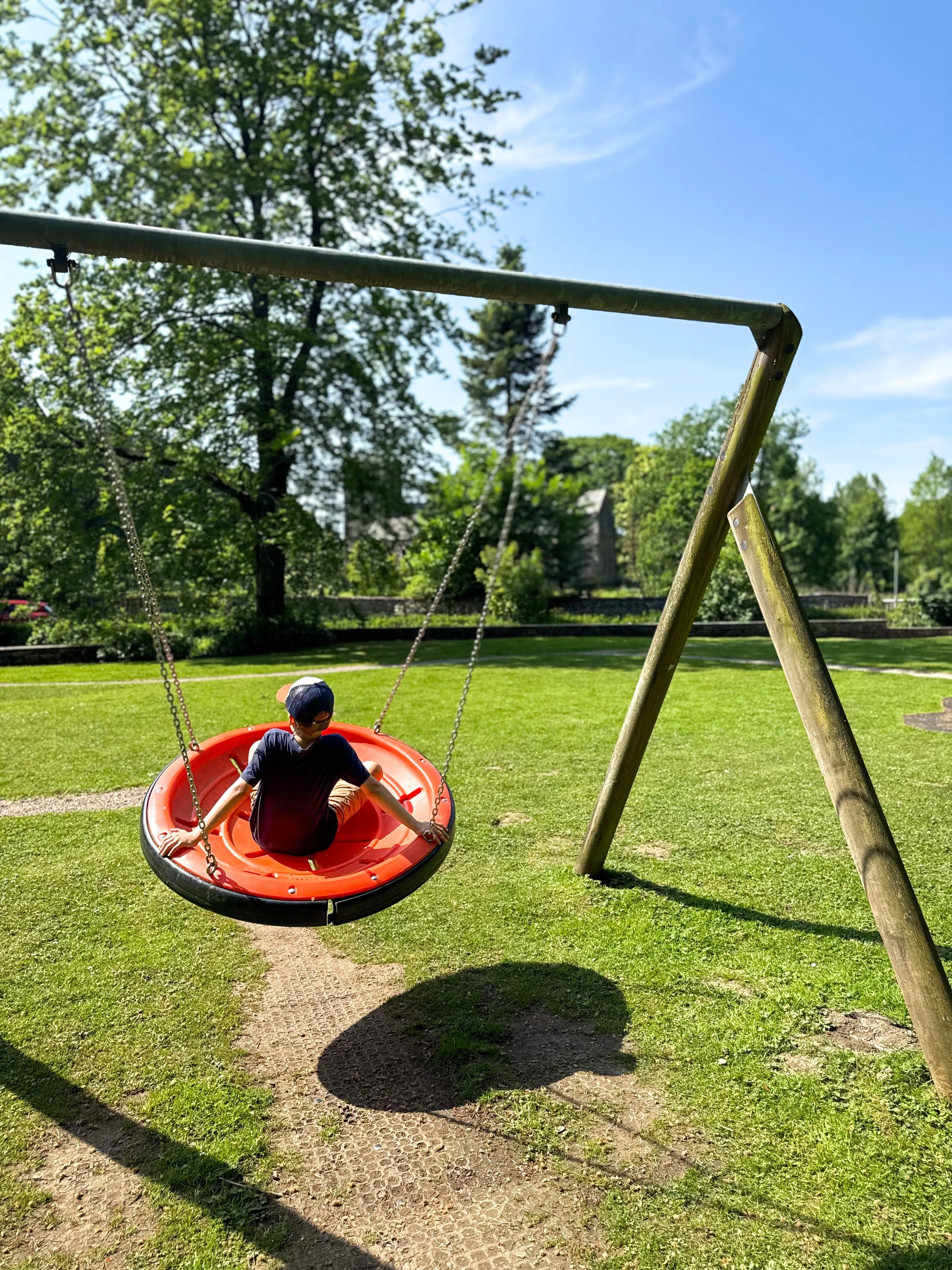 Child sitting on a swing with a church in the background