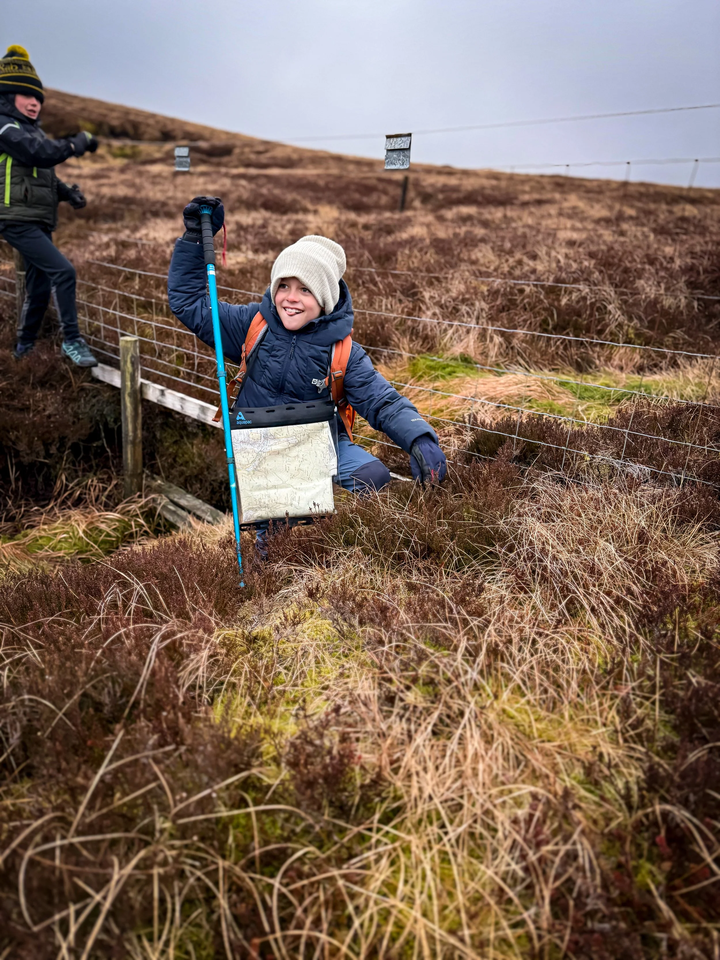 Child in a ditch using a hiking pole to climb out