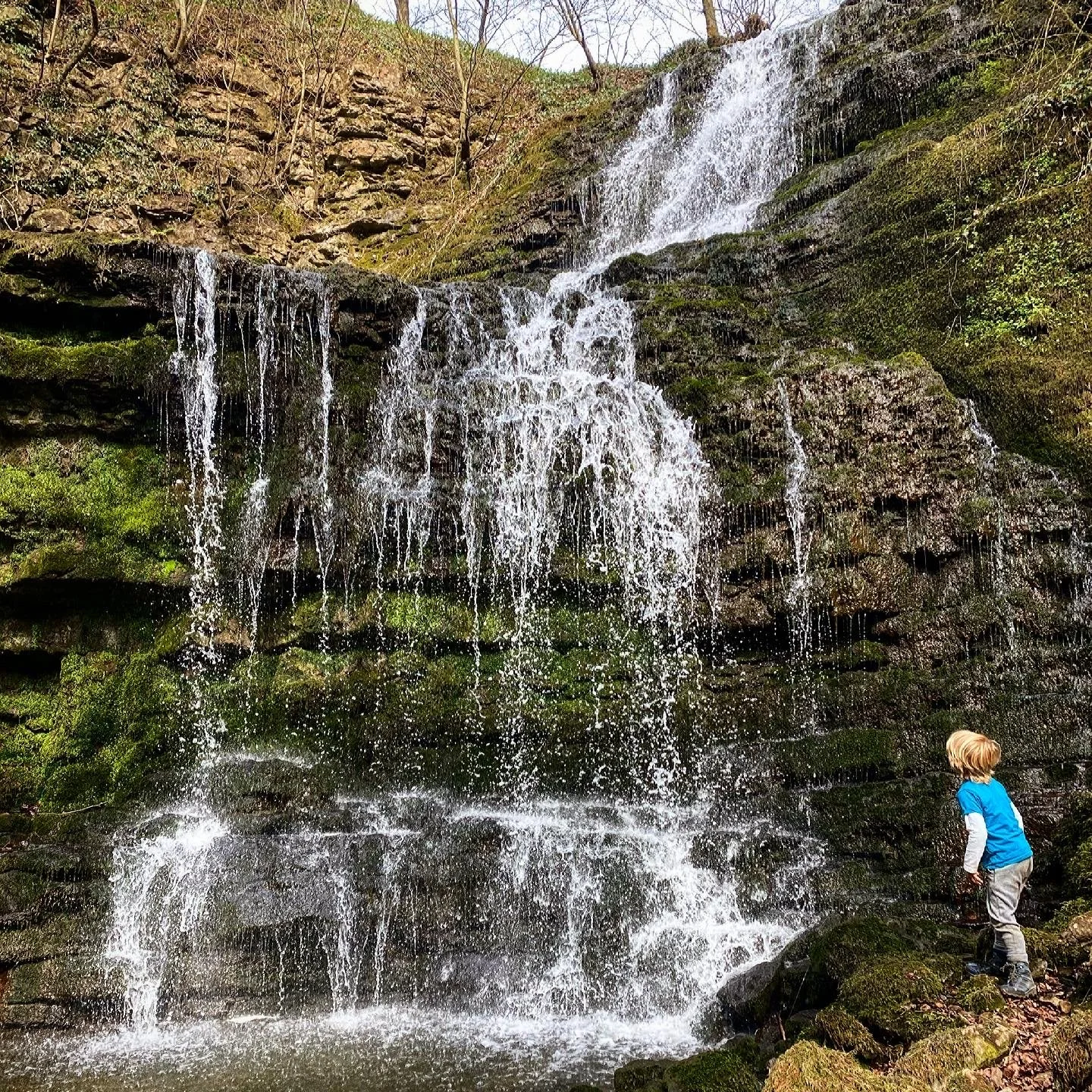 Child standing next to a large waterfall