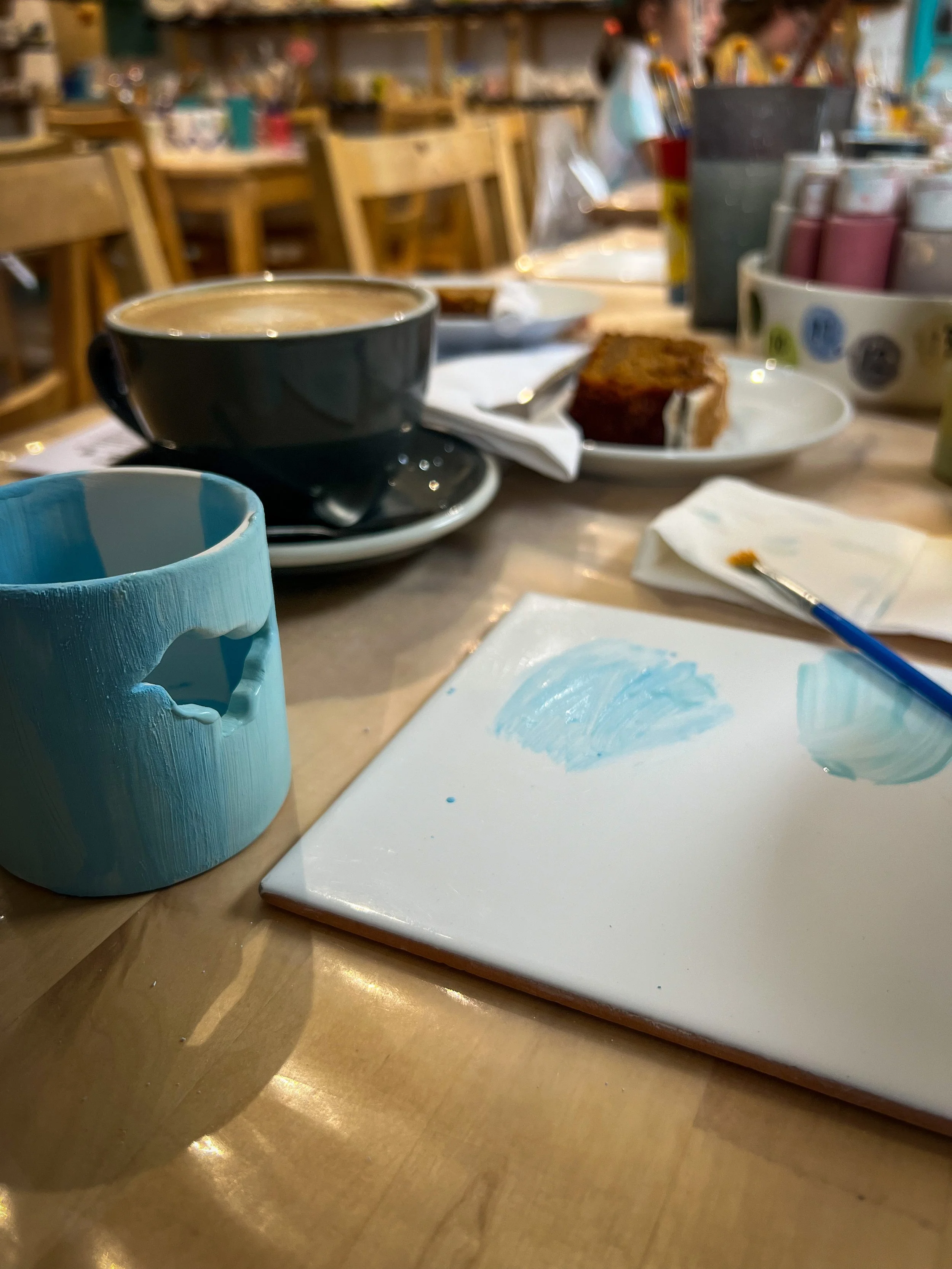 Pottery painting with a coffee and a partly finished tealight holder with paint