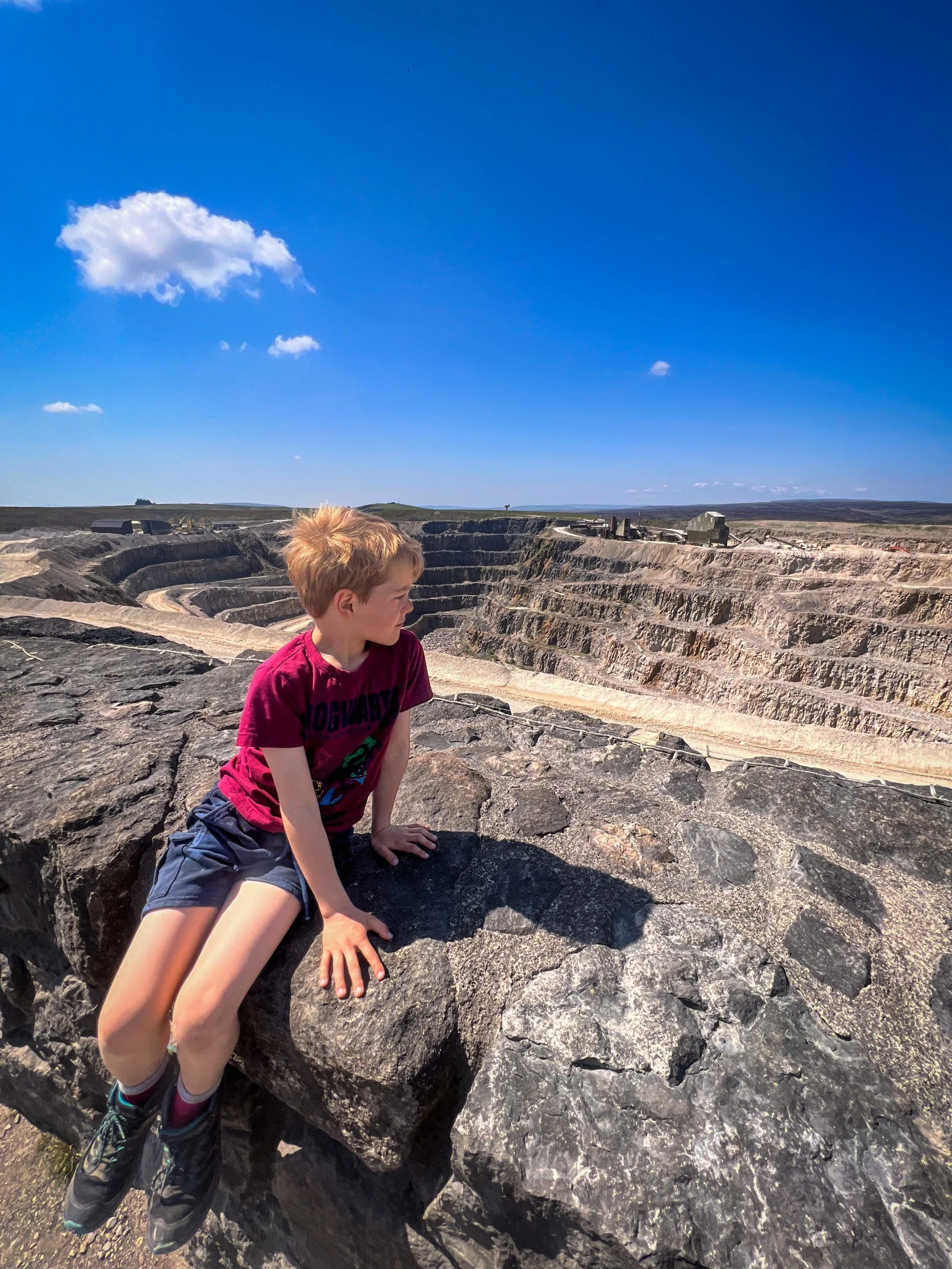 Boy sat on the edge of a quarry on a wall