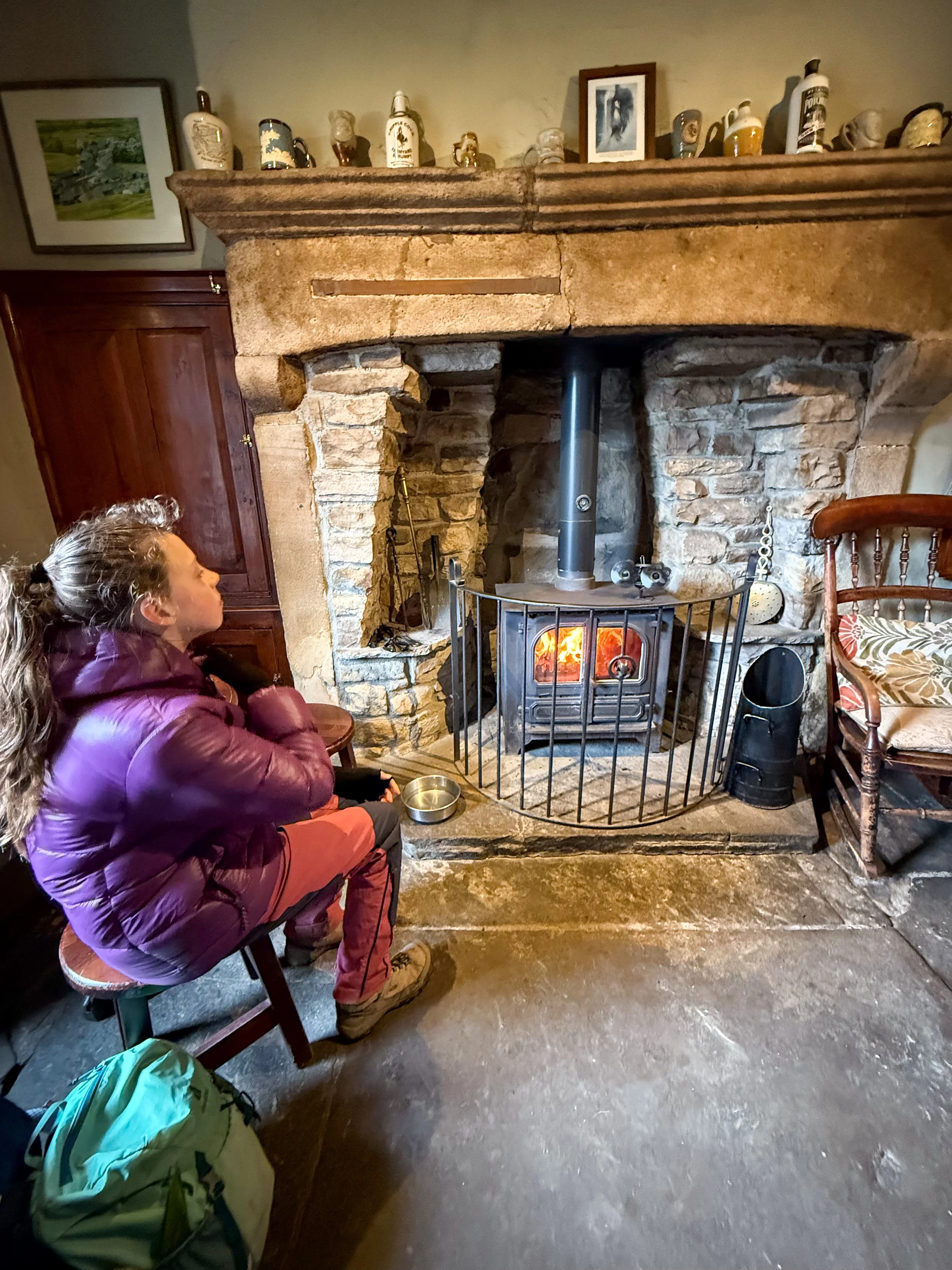 Child warming up in a pub next to a cosy fire
