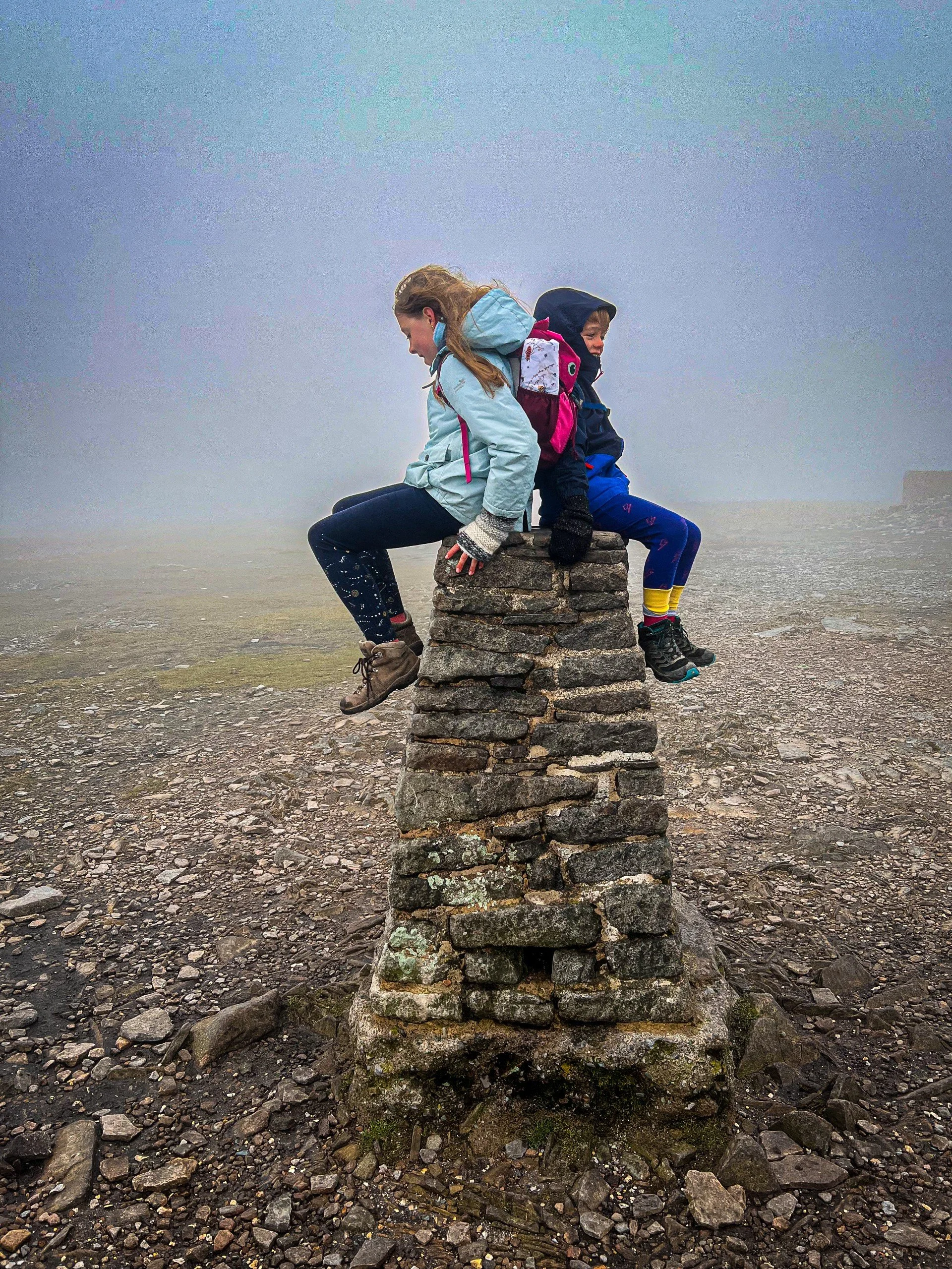 Ingleborough trig with two children sitting on top