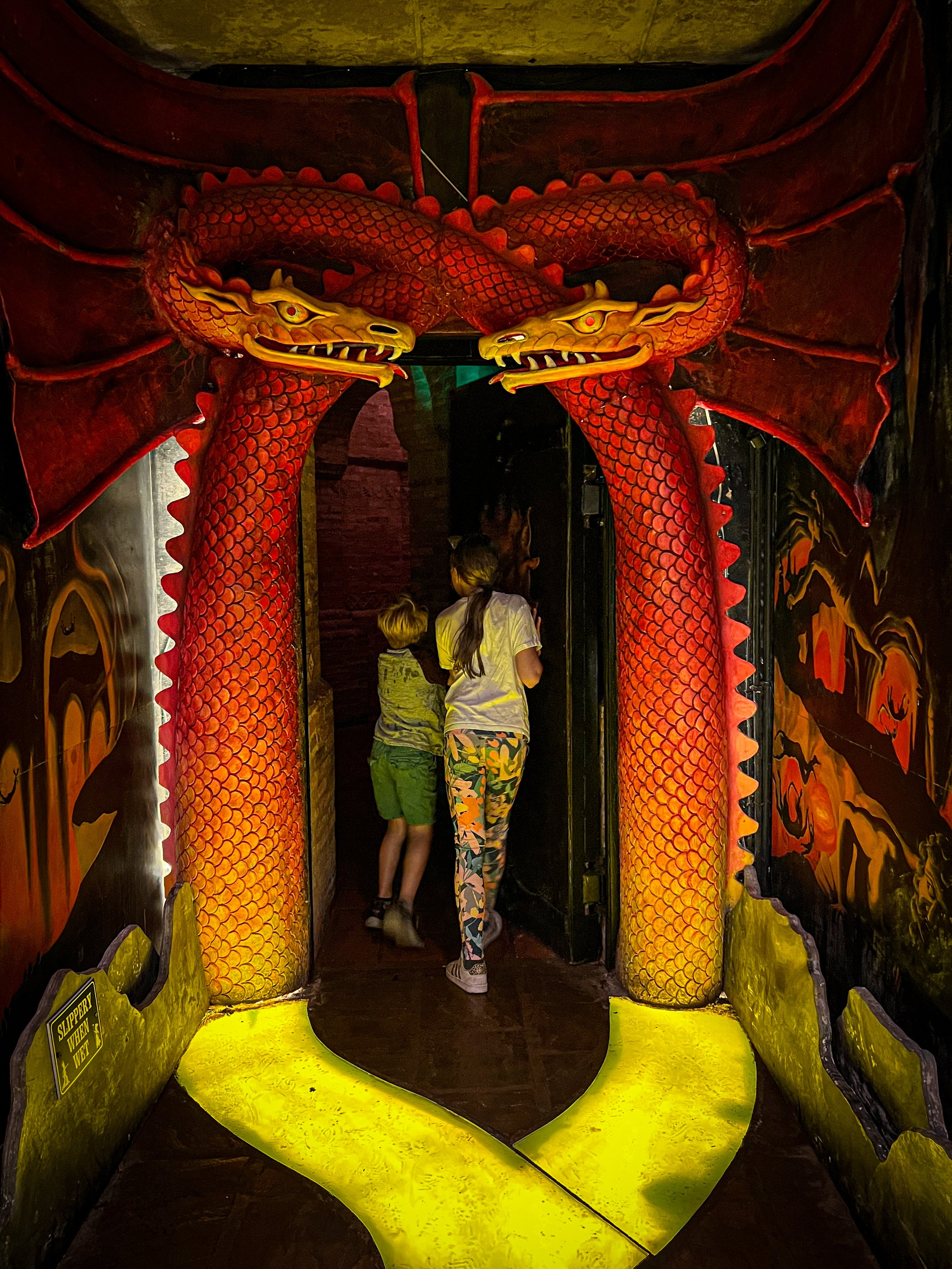 Children walking through an orange door surrounded by dragons