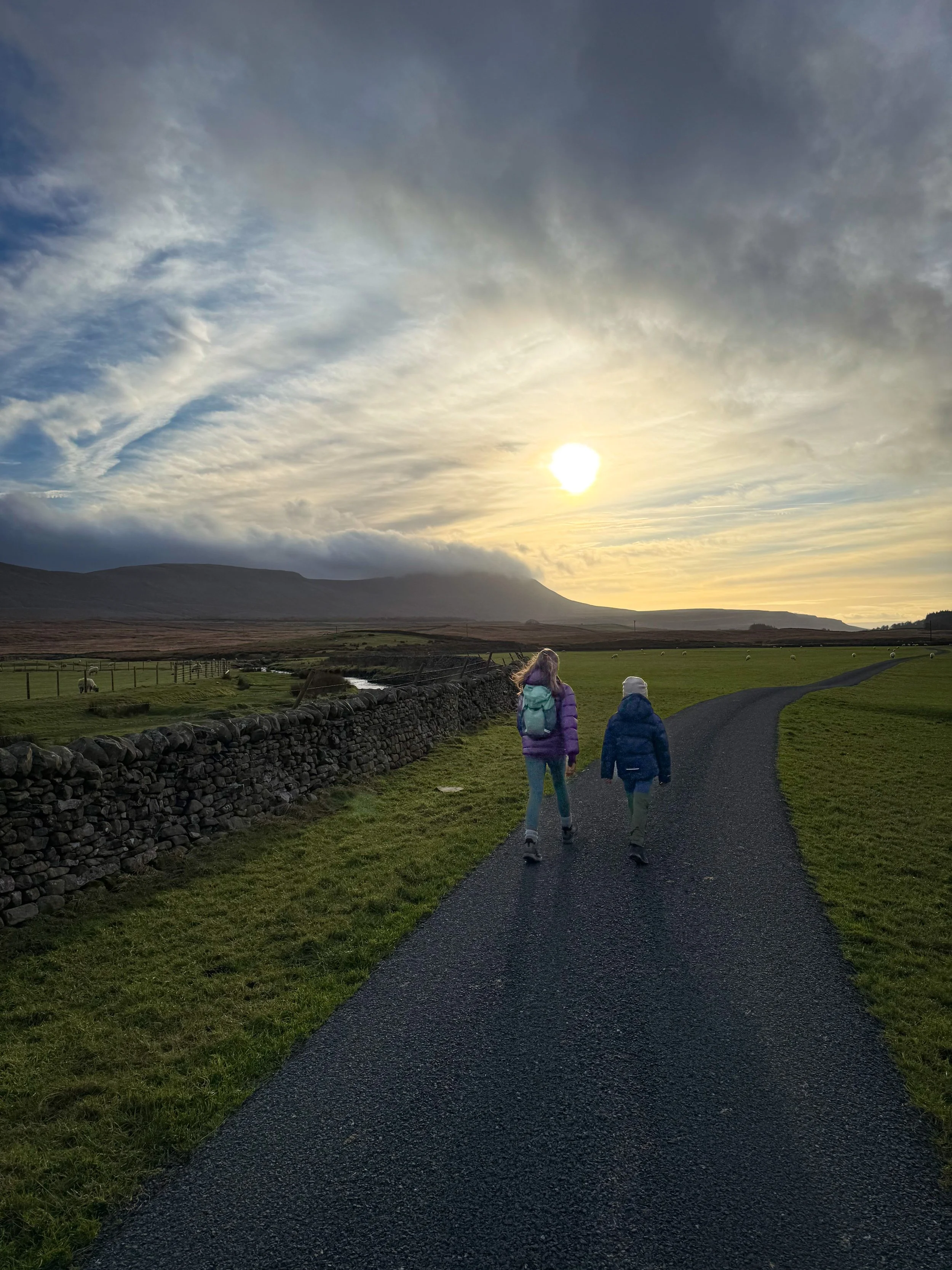 Children walking in low winter light with Ingleborough mountain in the distance