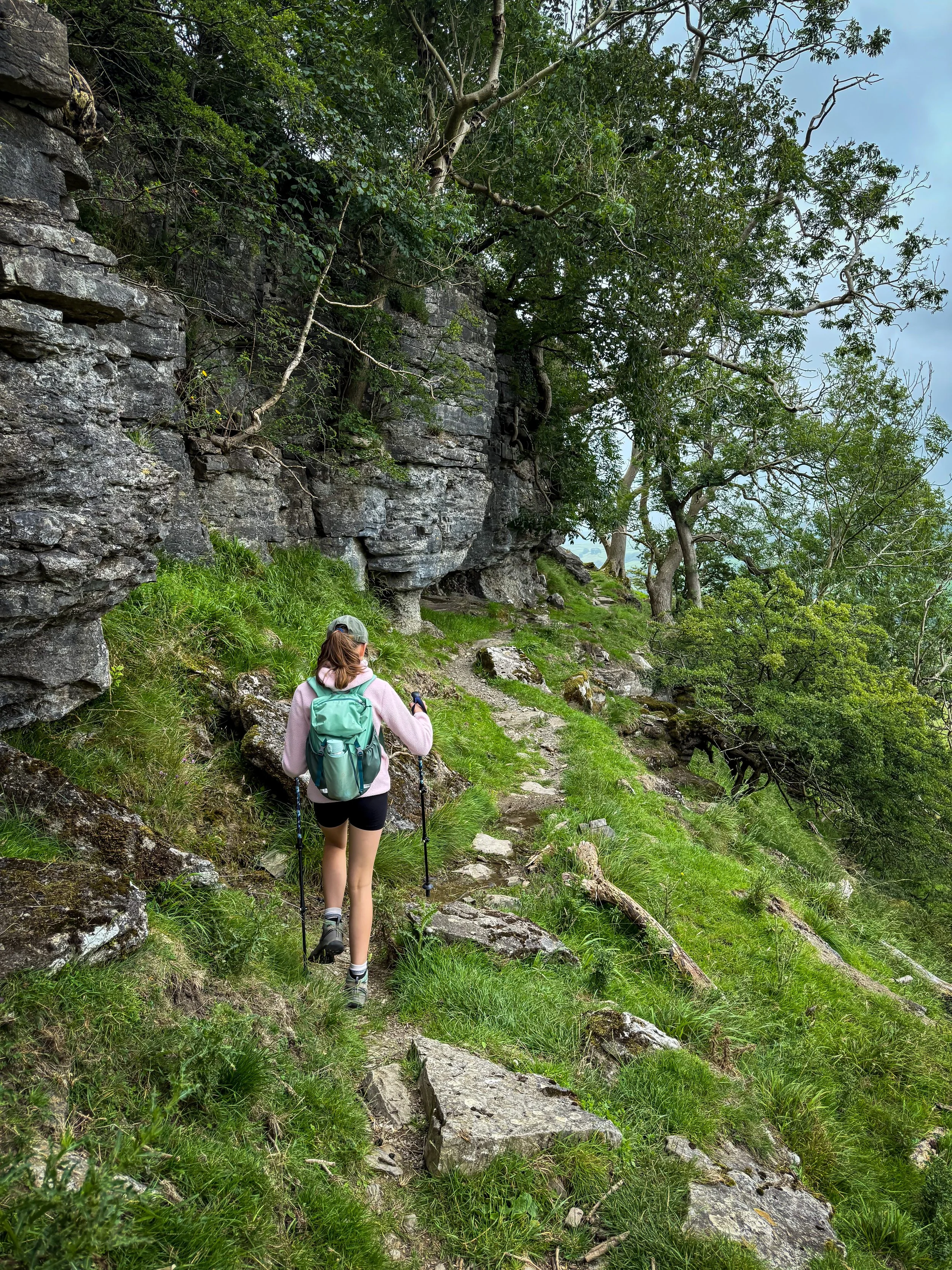 Child walking along the edge of a rocky scar with bushes