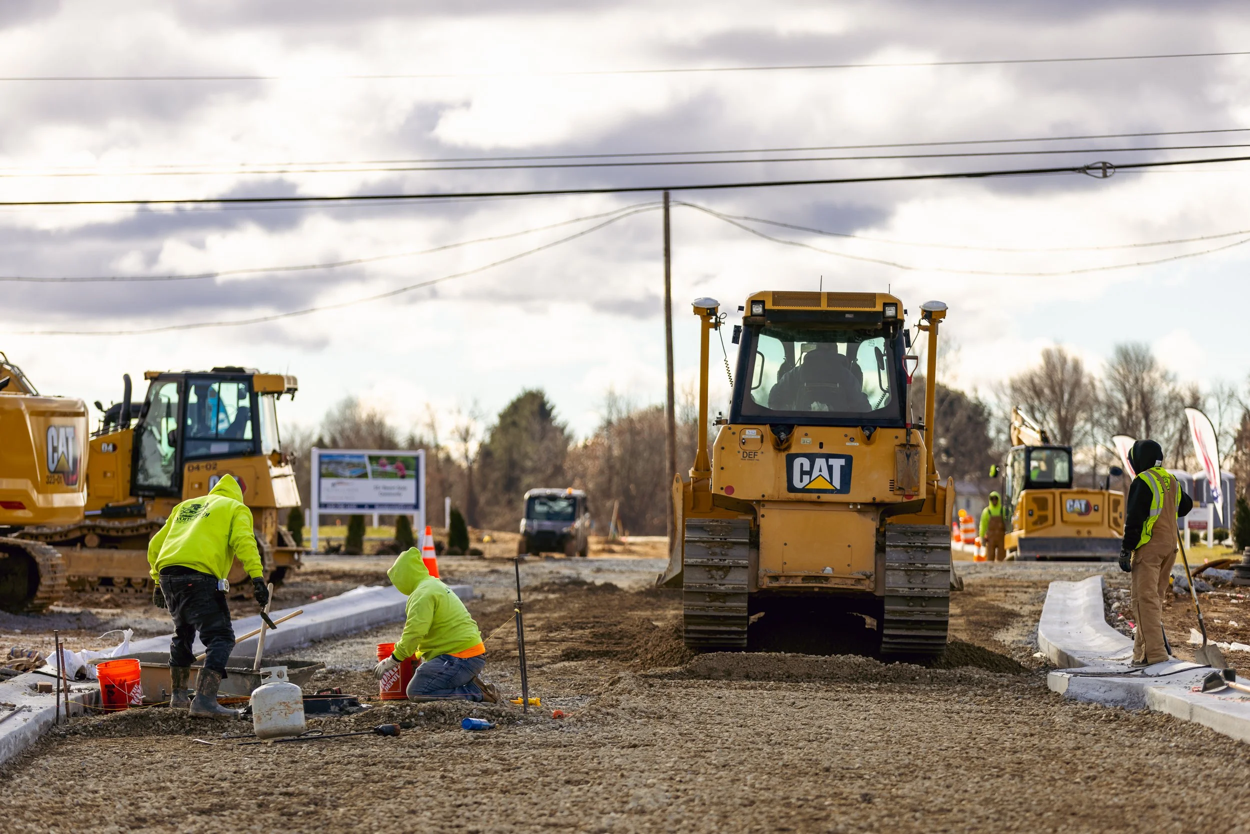 Setting manholes to grade after the curb is up while we place the road sub-base material with dozers.