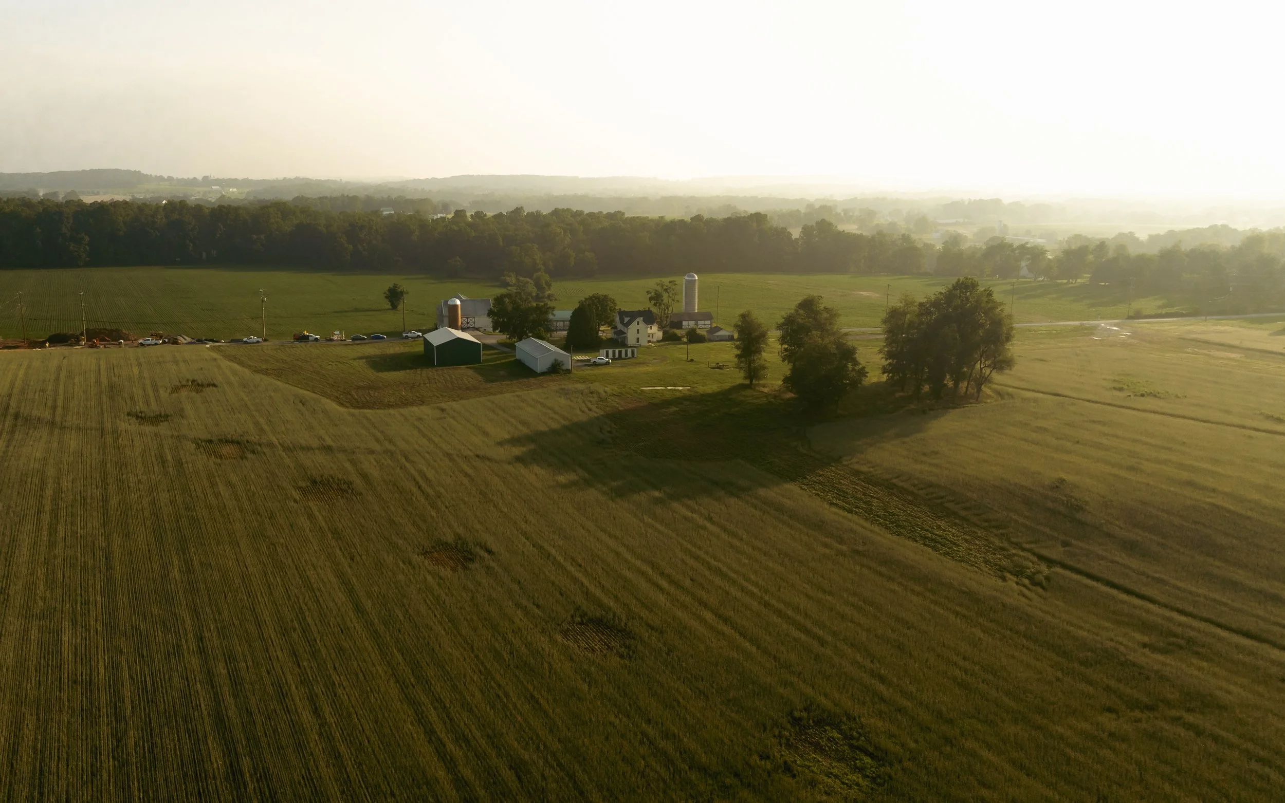 Scenic sunrise view of the current farms at Harvest Run, a future jobsite in Chester County for Traditions of America. The serene landscape bathed in the morning light presents the untouched beauty of the site before our construction work begins.