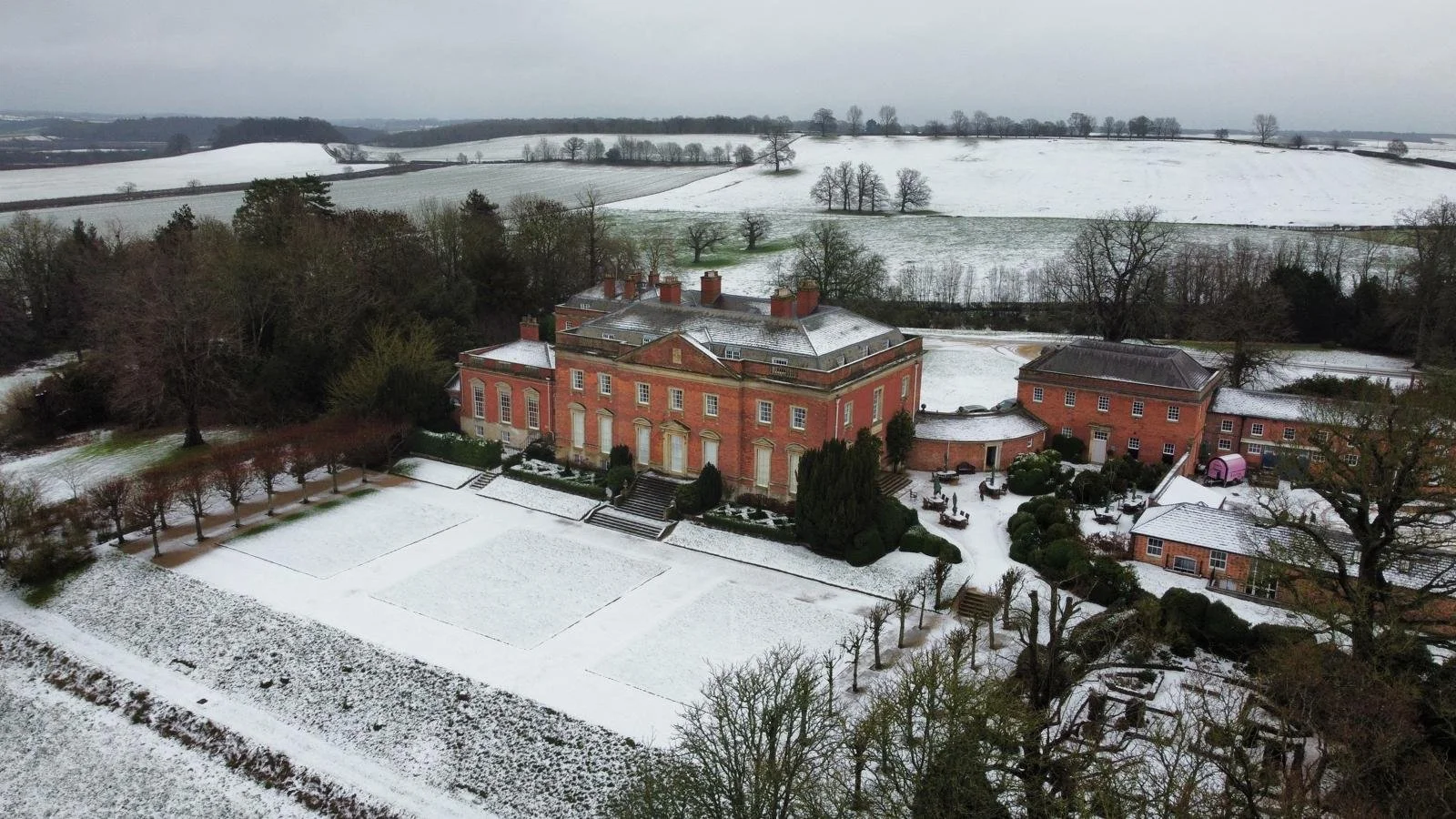 An aerial shot of Kelmarsh Hall with snow settled on the ground