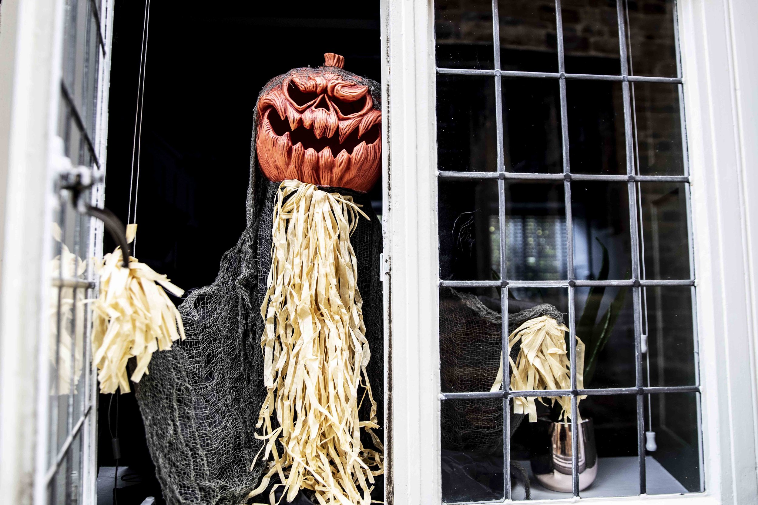 A pumpkin headed spooky character looking out of one of the Abbey's leaded windows
