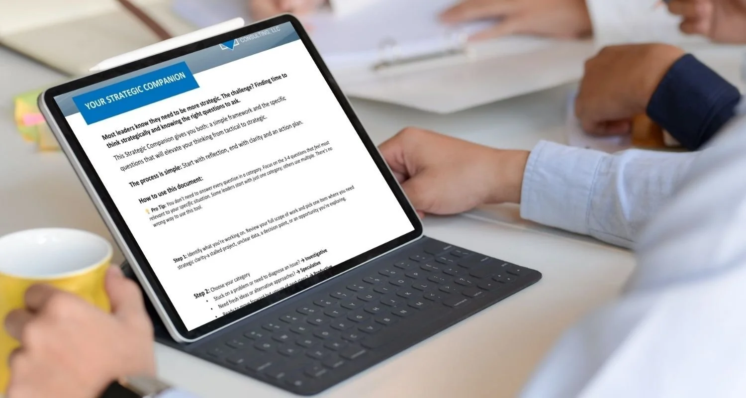 A person using a tablet with a keyboard attachment to read a document titled "Your Strategic Companion" at a meeting table with other people.
