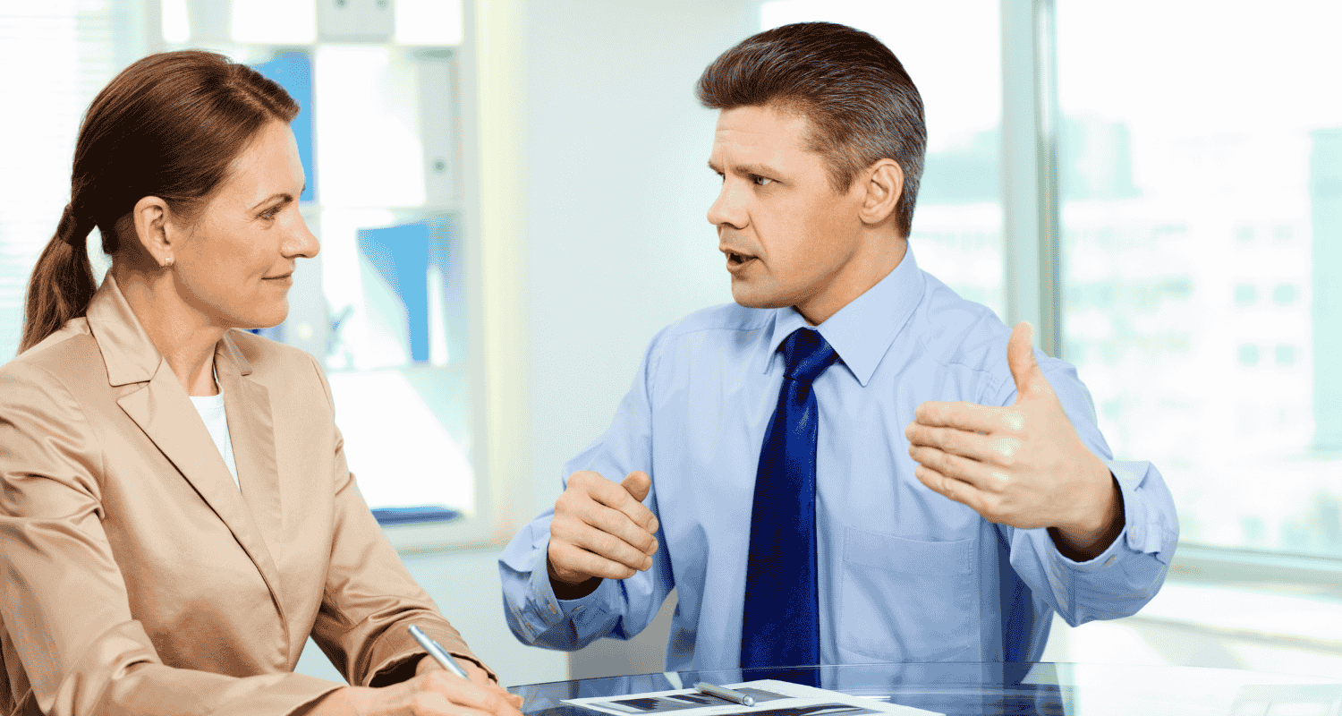 Man in blue shirt and tie talking with woman in tan blazer