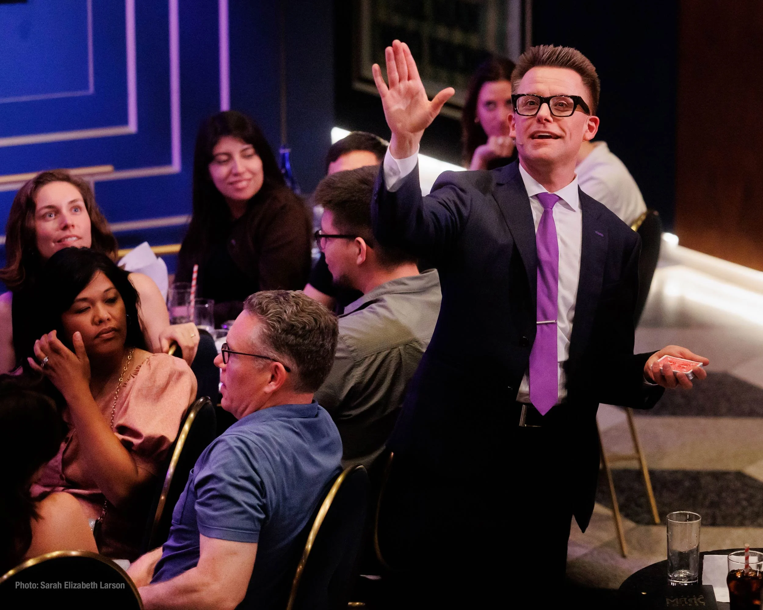 Arthur Trace performing a card trick in the middle of an audience.