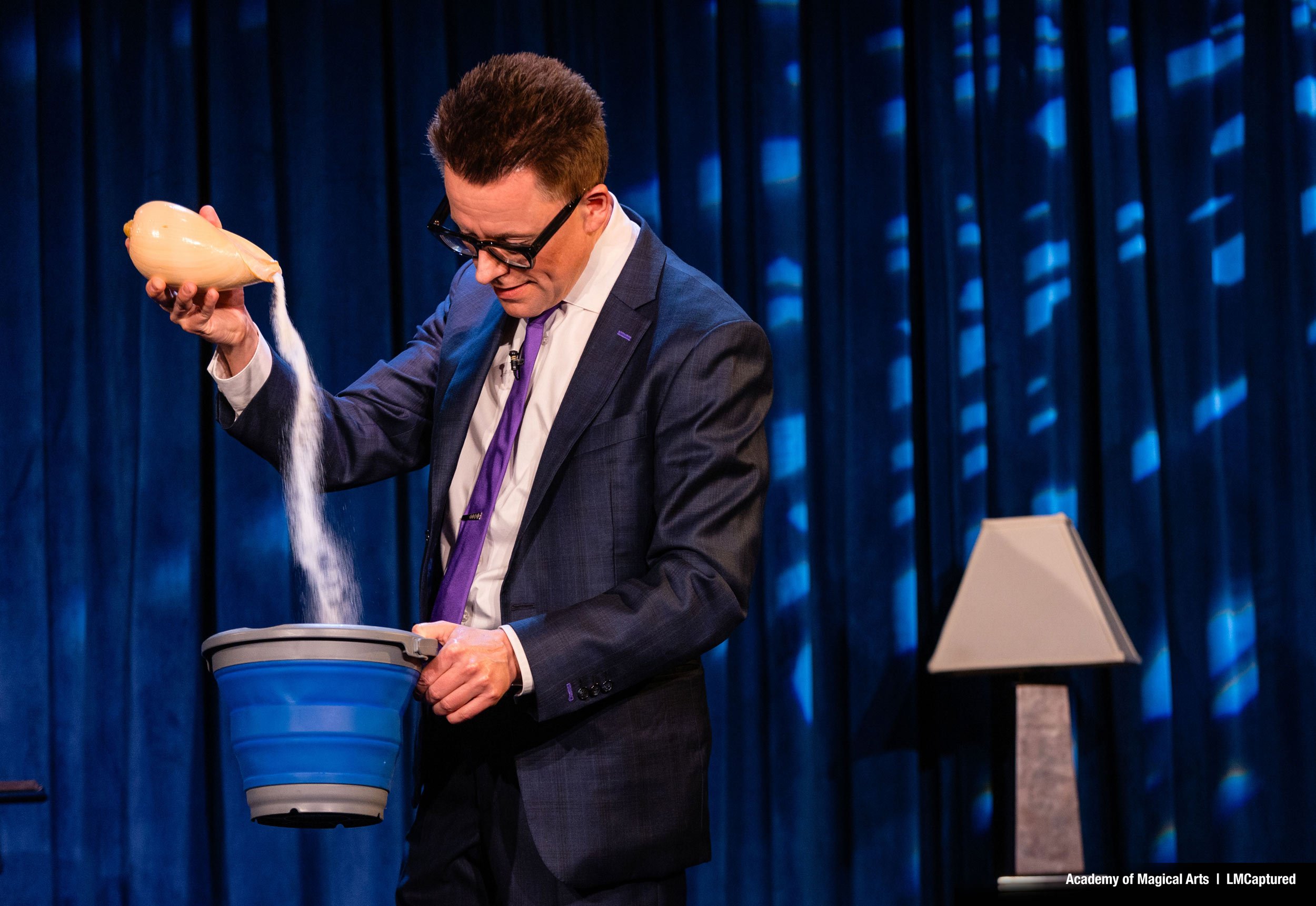 Arthur Trace pours sand from a conch shell into a bucket.
