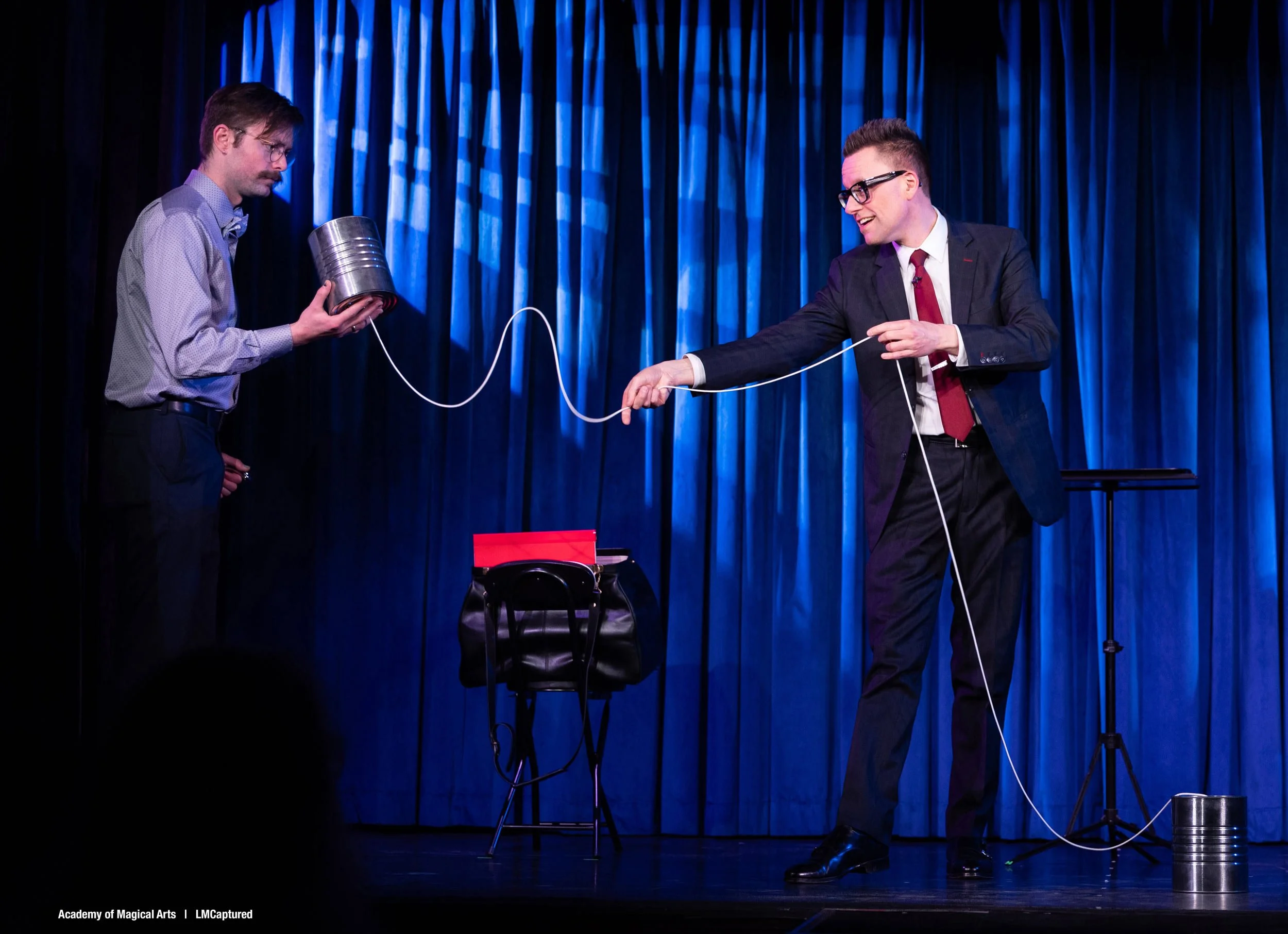 Arthur Trace and a male volunteer on stage at The Magic Castle's Palace of Mystery Theater. Arthur is performing a routine with a tin can telephone.