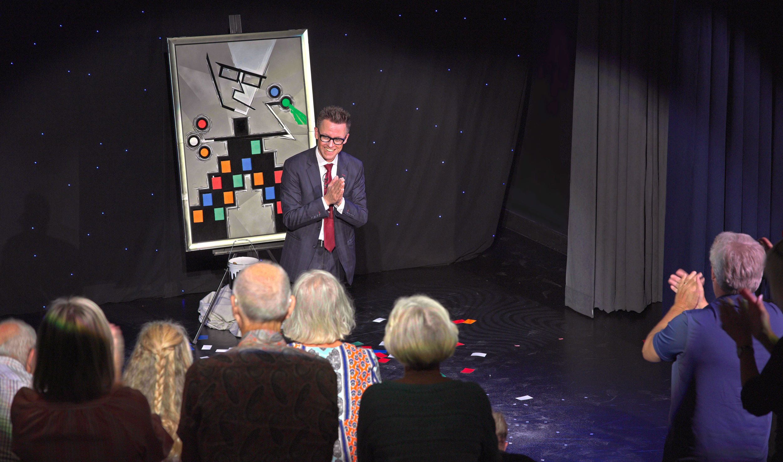 Arthur Trace is standing on stage at the end of his show. The audience is giving him a standing ovation.