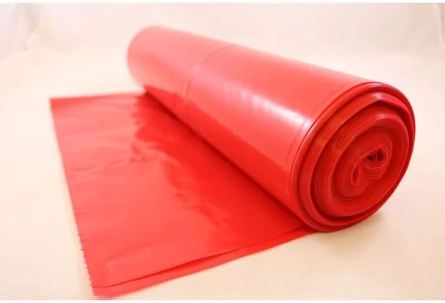 Rullet af pink plastfolie liggende på en hvid overflade.