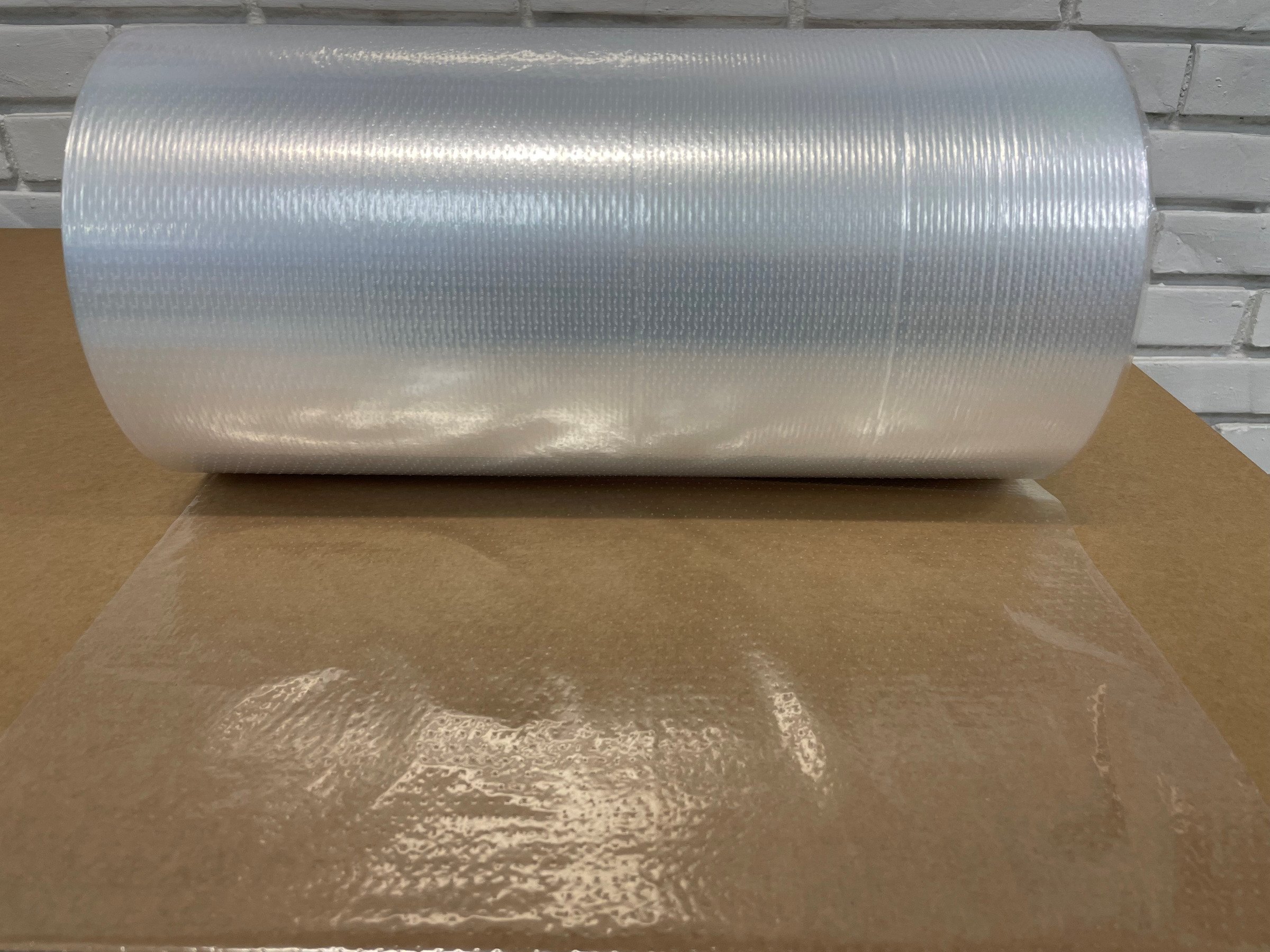 Et rullende stykke reflekterende materiale, der ligger på en brunt bord, foran en hvid murvægsbaggrund.