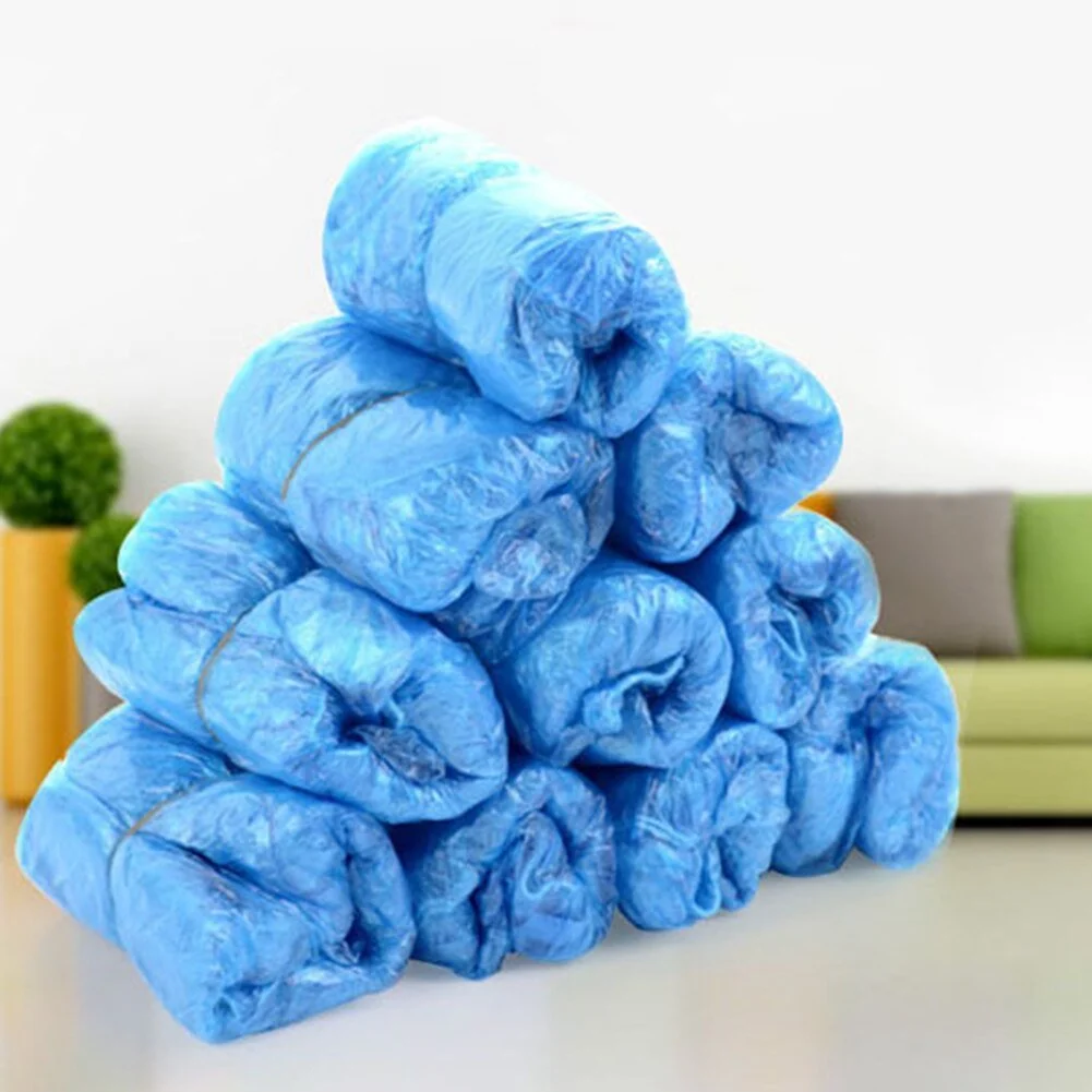 En bunke af blå affaldsposer stablet op på en bord i et hjem, med en grøn sofa og to grønne planter i baggrunden.