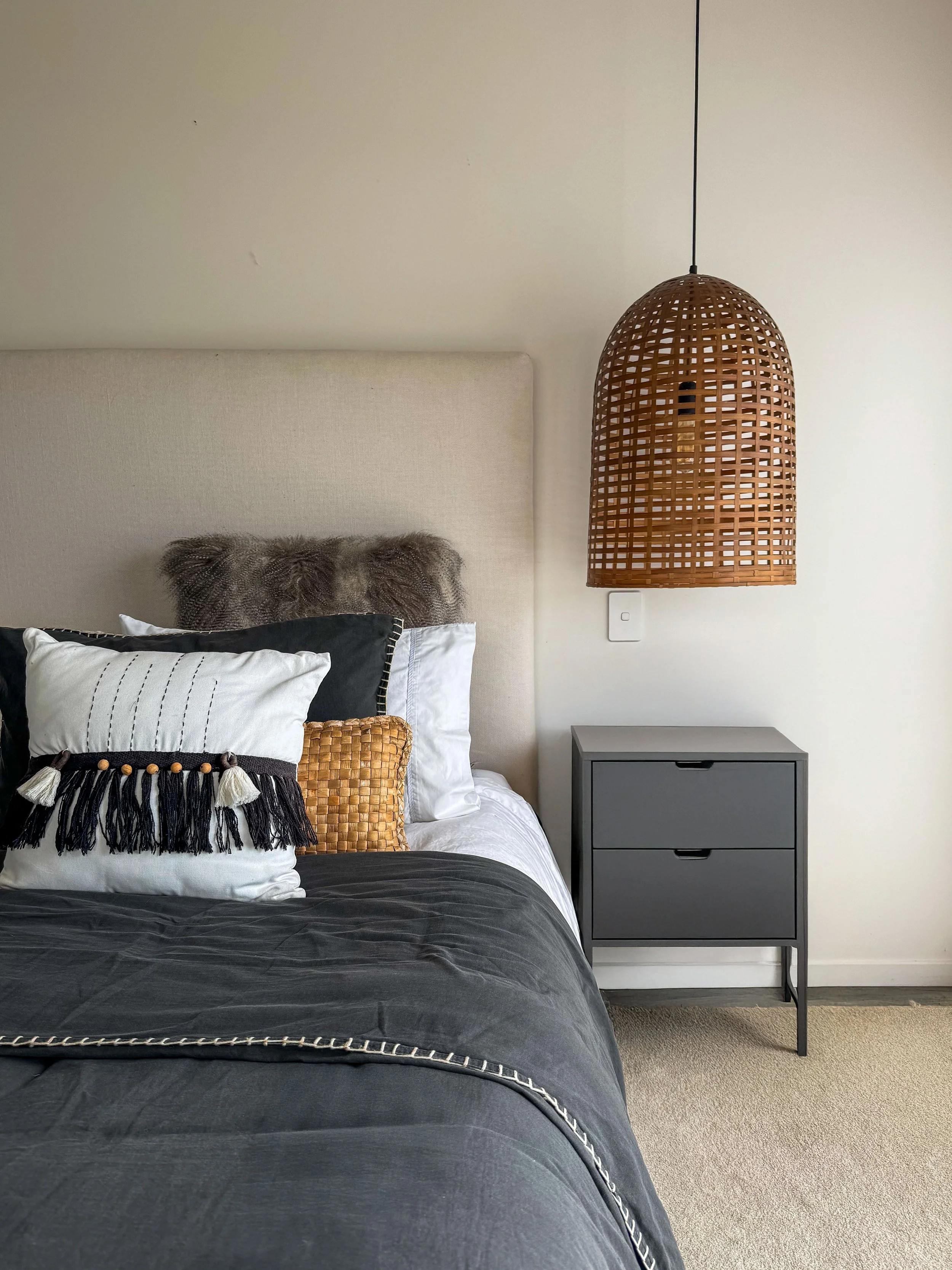 Grey and neutral bedroom interior with custom bed head and layered cushions