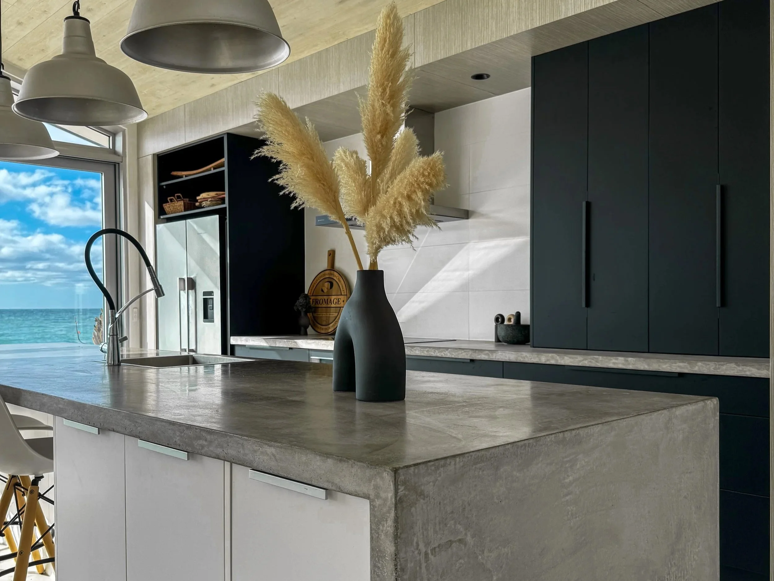 Modern kitchen with green lower cabinets, white upper cabinets, marble backsplash, built-in oven, wine cooler, and gas stove, with a sink and under-cabinet lighting.