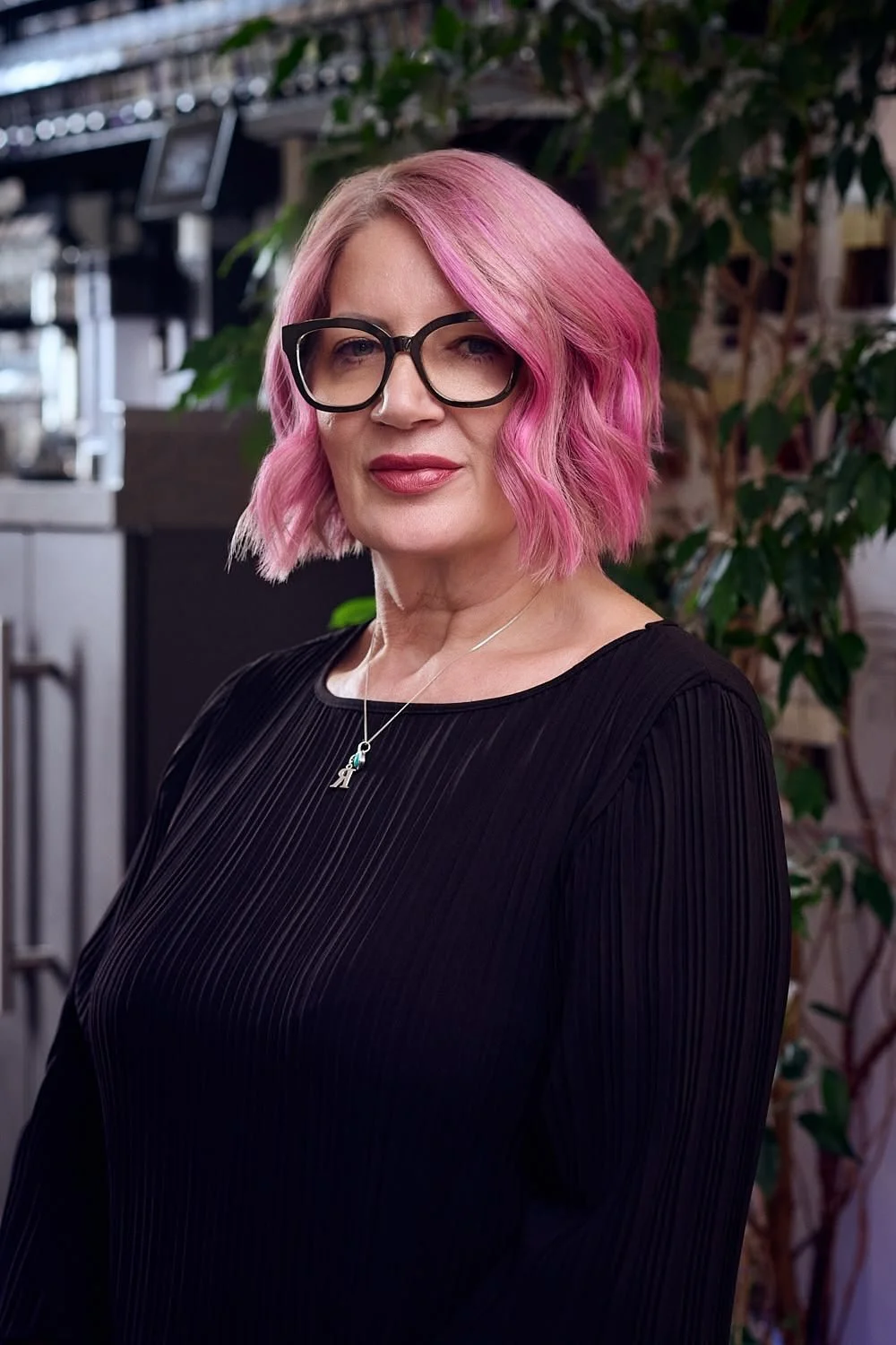 Woman with pink hair standing against a cupboard in Tenterden
