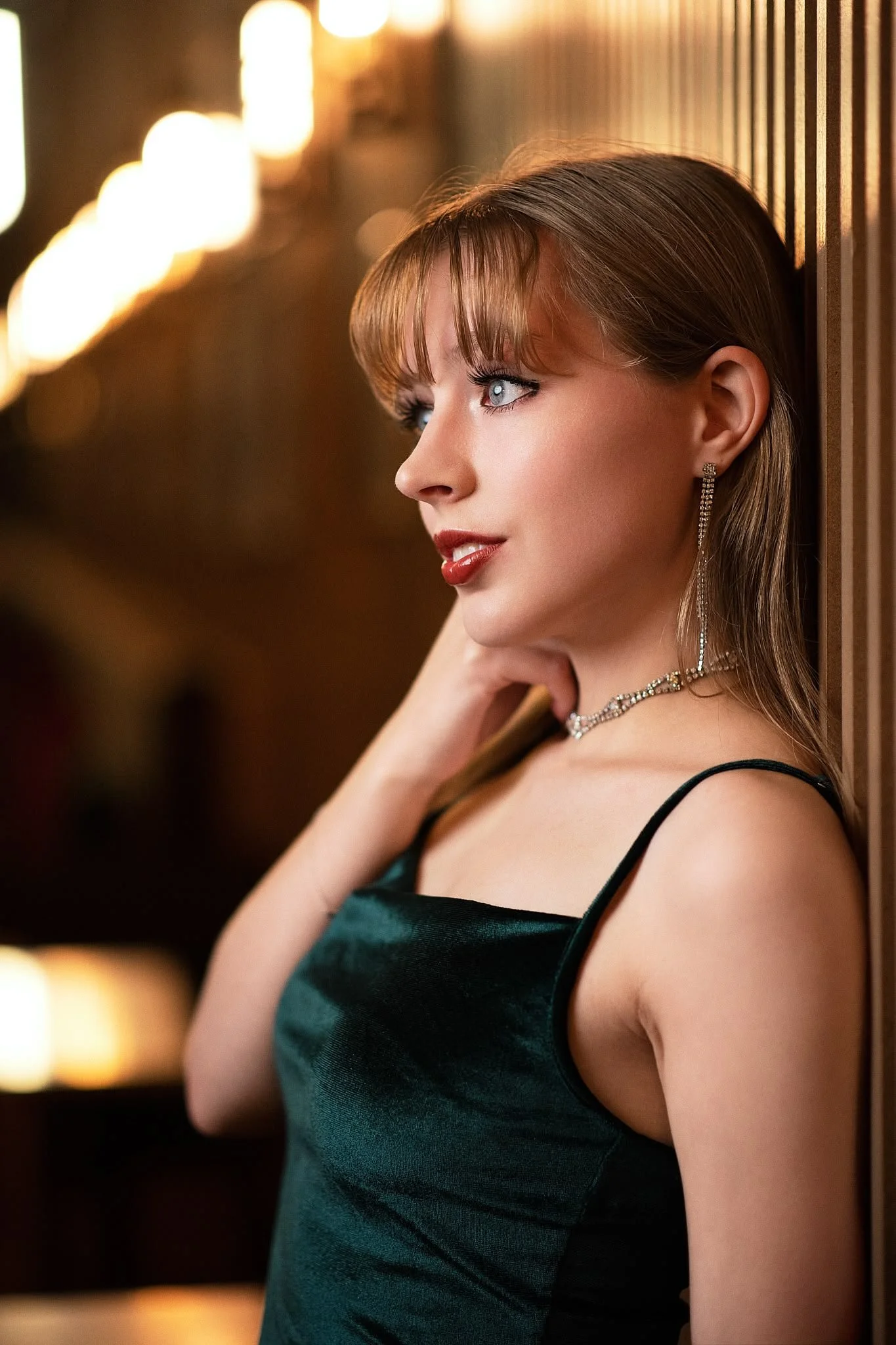 Blond woman with red lipstick leaning against wall