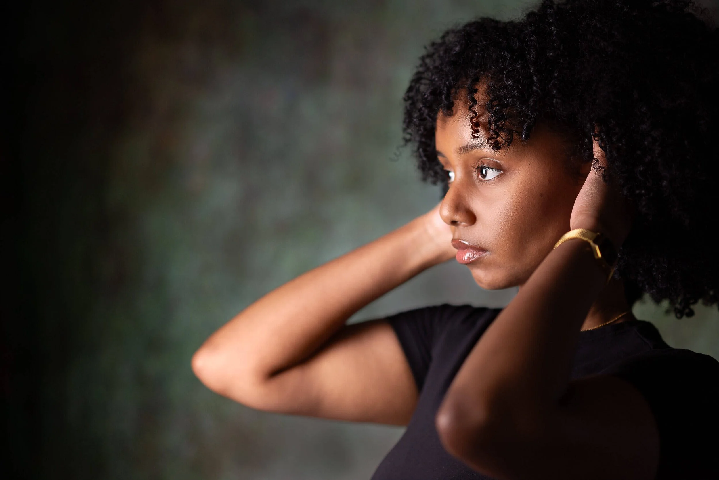 Woman with black tank top with hands in her afro