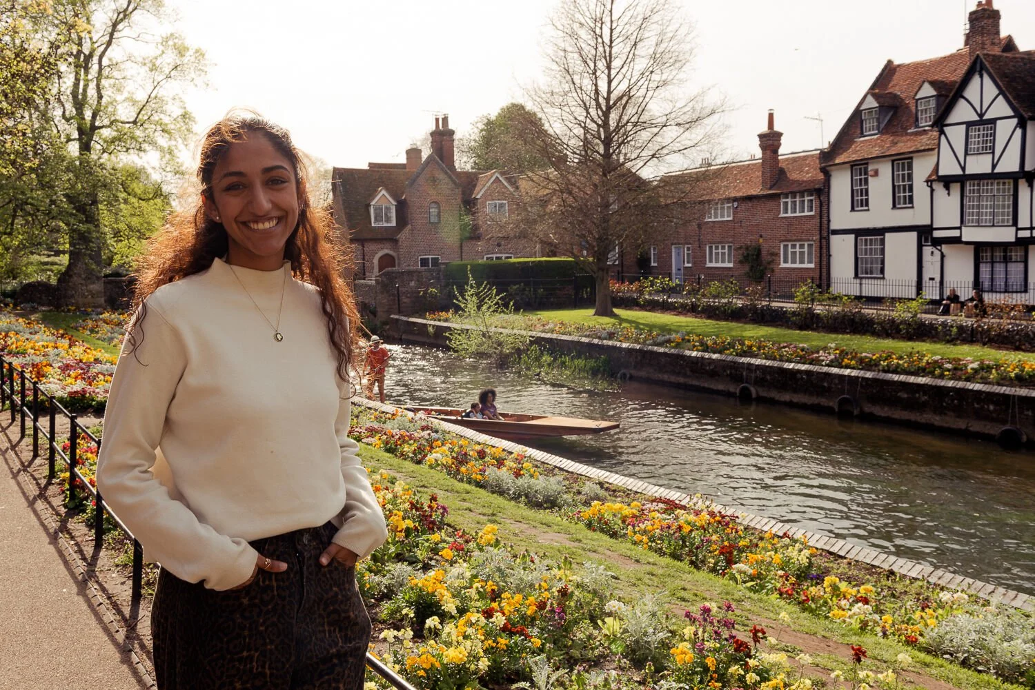 Woman smiling at camera by a punt turning on the river Stour