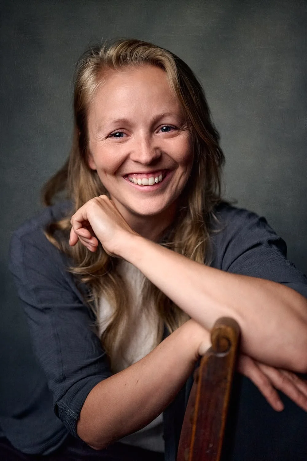 Blond woman in a chair laughing into the camera shot by Chris Henry Photography