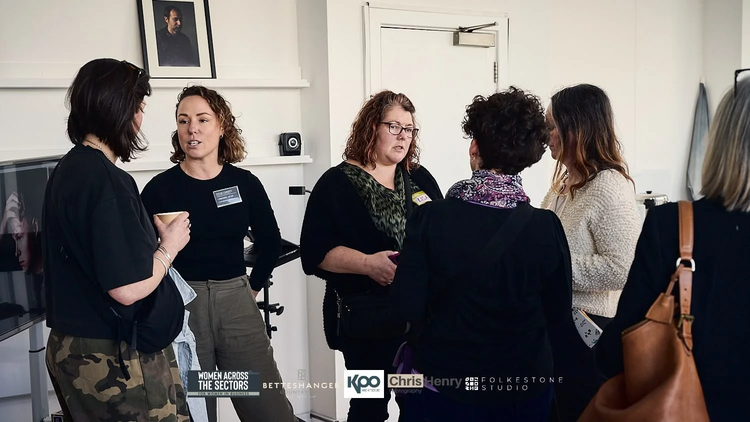 Group of women engaged in conversation indoors at a professional event or gathering.