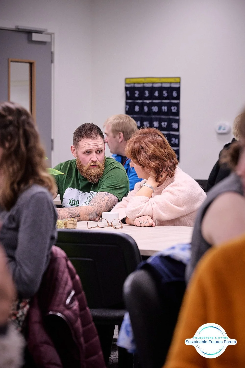 A group of people sitting at a conference table engaged in conversation during a meeting.