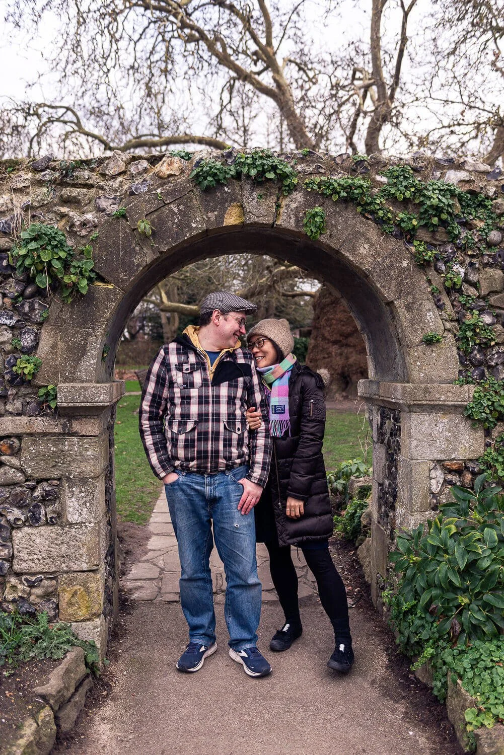 Man and woman smiling at each other under a stone arch