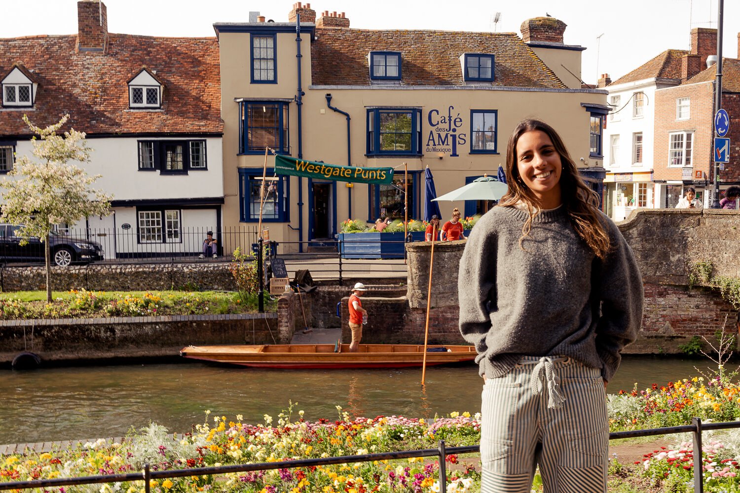 Woman smiling against the backdrop of a restaurant, a river and a punt