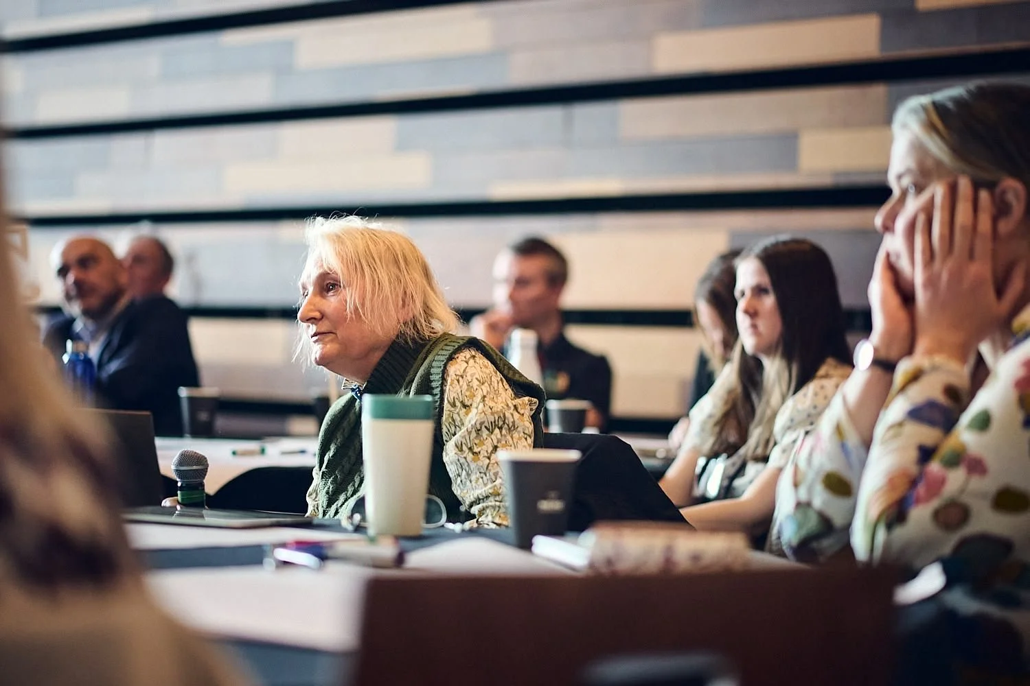 Group of people sitting at a conference table, listening attentively.