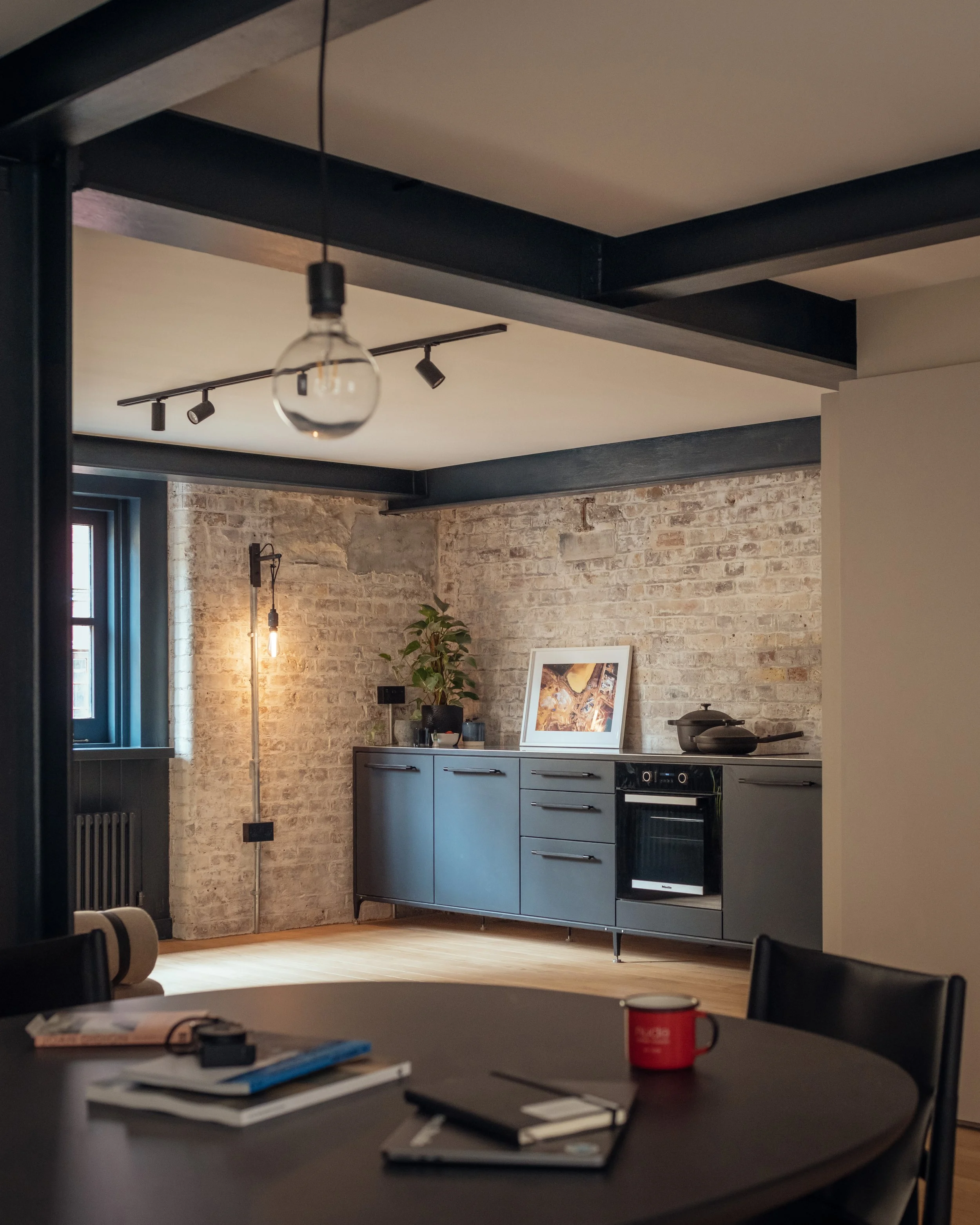 Image of refurbished wharf building with exposed brickwork, steel beams, oak floor. Modern Buster & Bunch kitchen to right of the image.