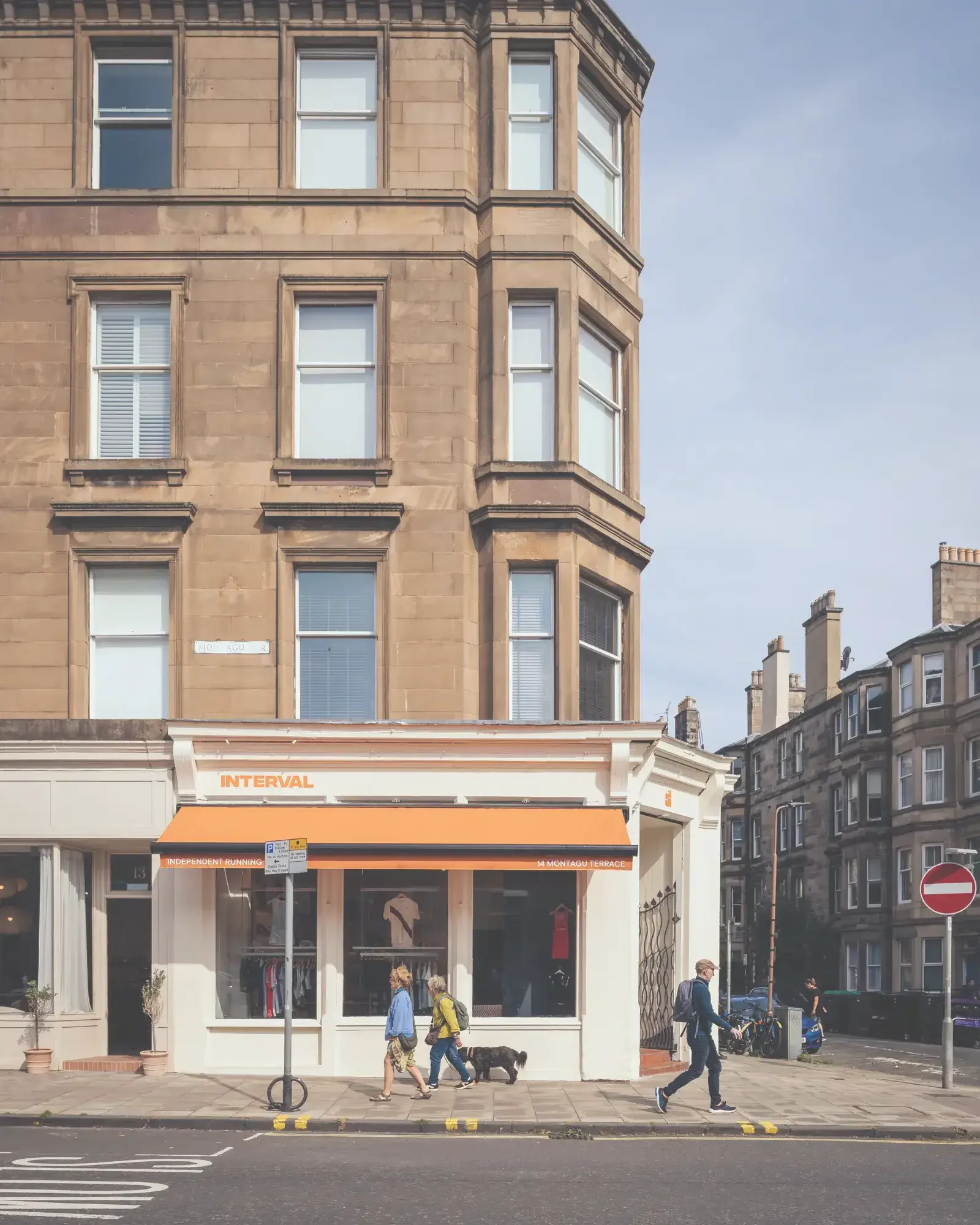 External elevation photo of a running shop in Edinburgh with an orange awning and orange Interval logo. 
