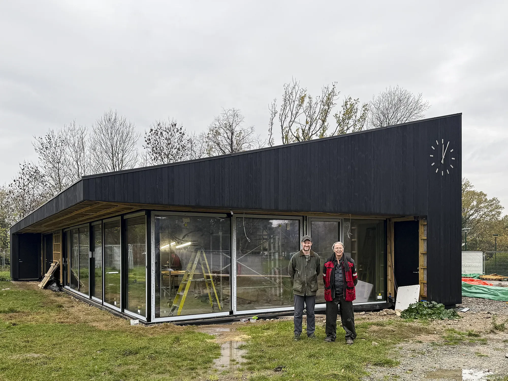 Clients stood in front of a partially completed cricket pavilion in Dulwich.