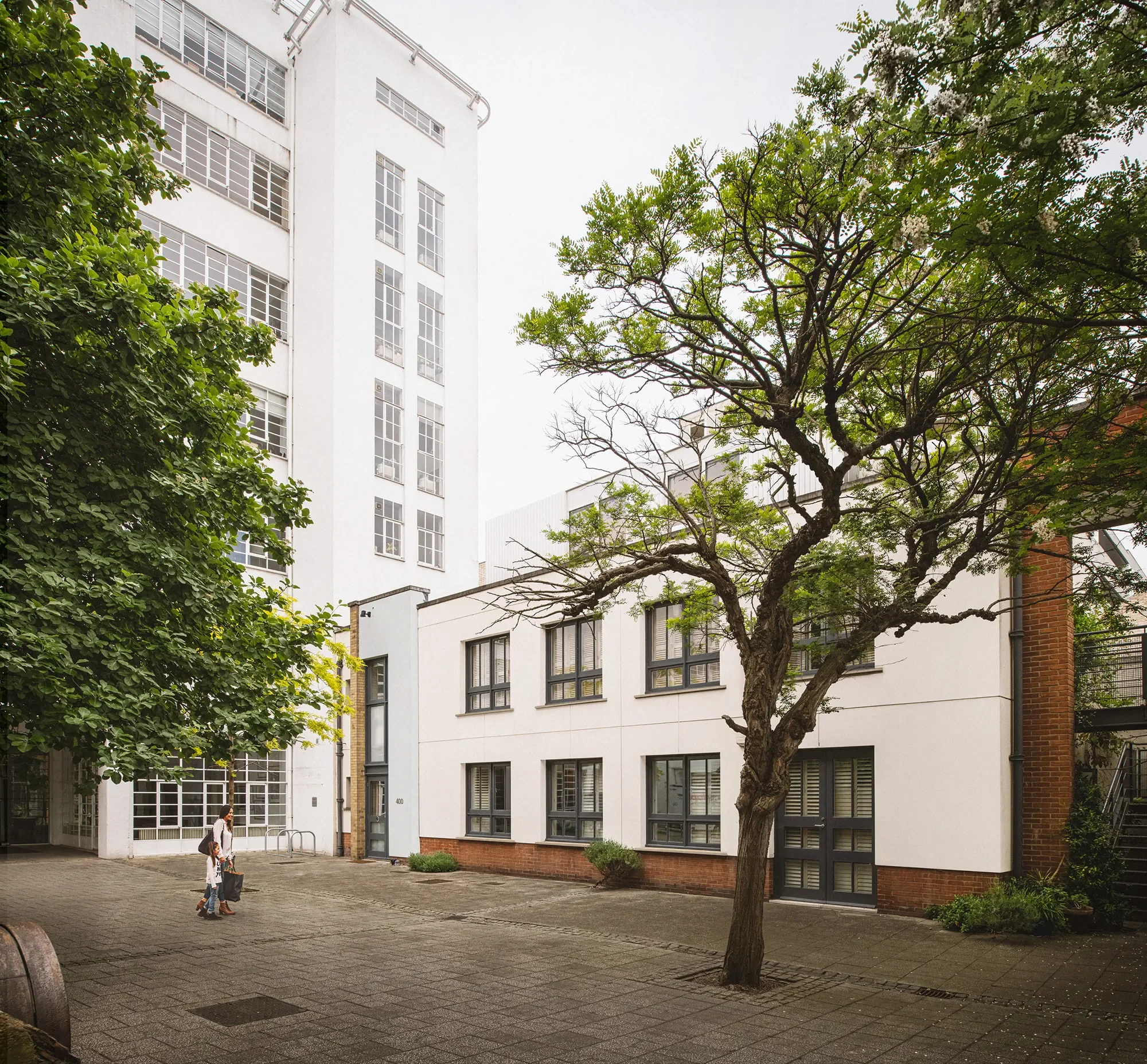 Alaska Factory courtyard view - existing two-storey building with Art Deco 600 building behind. New rooftop extension obscured by tree. © Tandem Studios