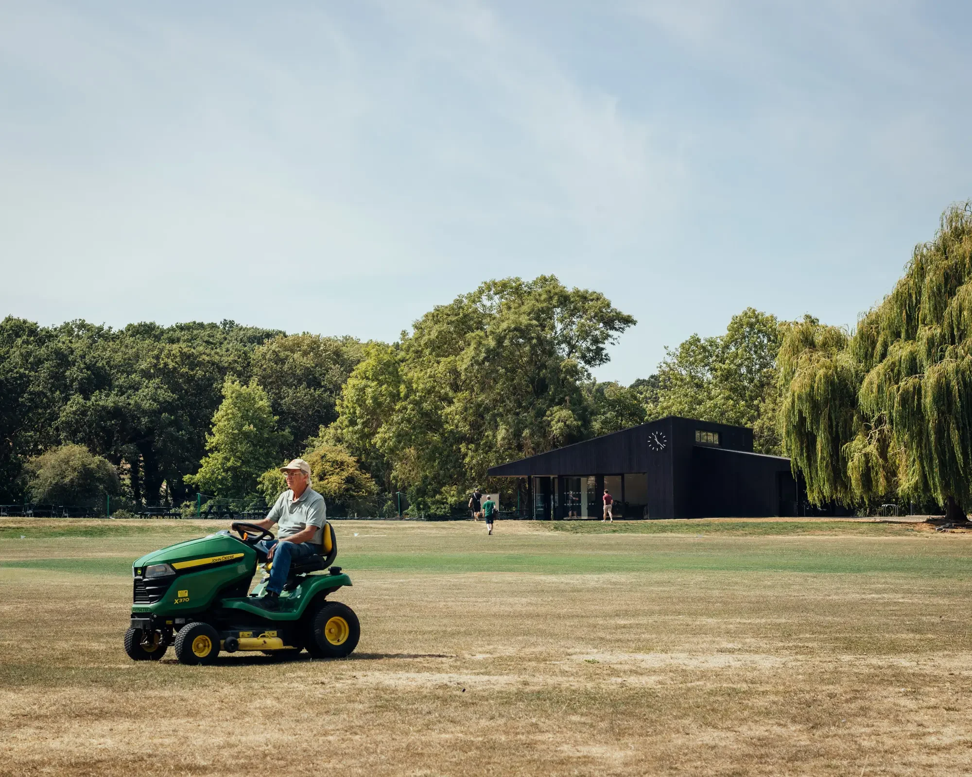 Cricket pavilion in landscape with grounds person in the foreground © Jim Stephenson