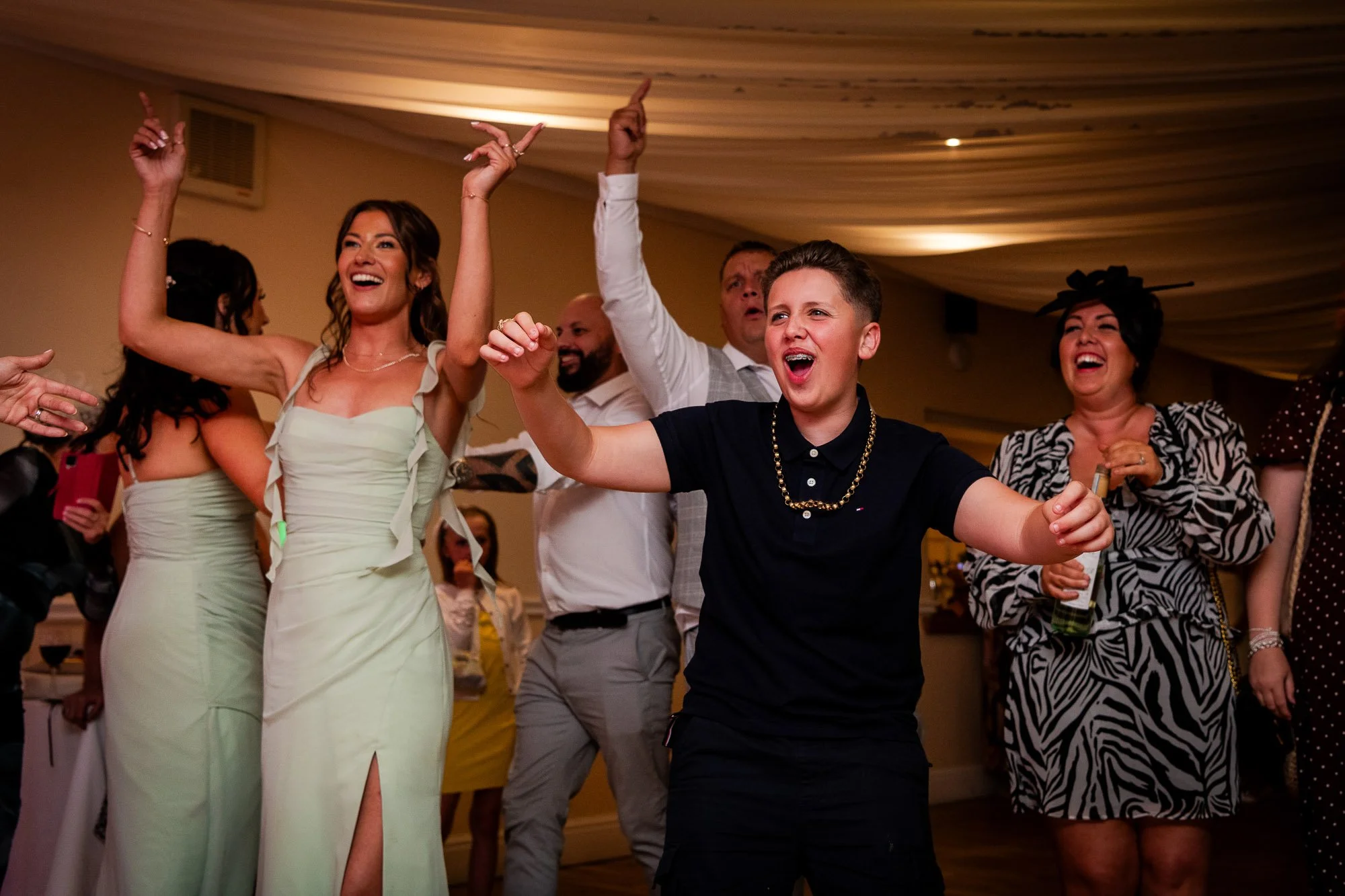 People dancing and celebrating at a party or wedding reception, smiling and enjoying themselves.