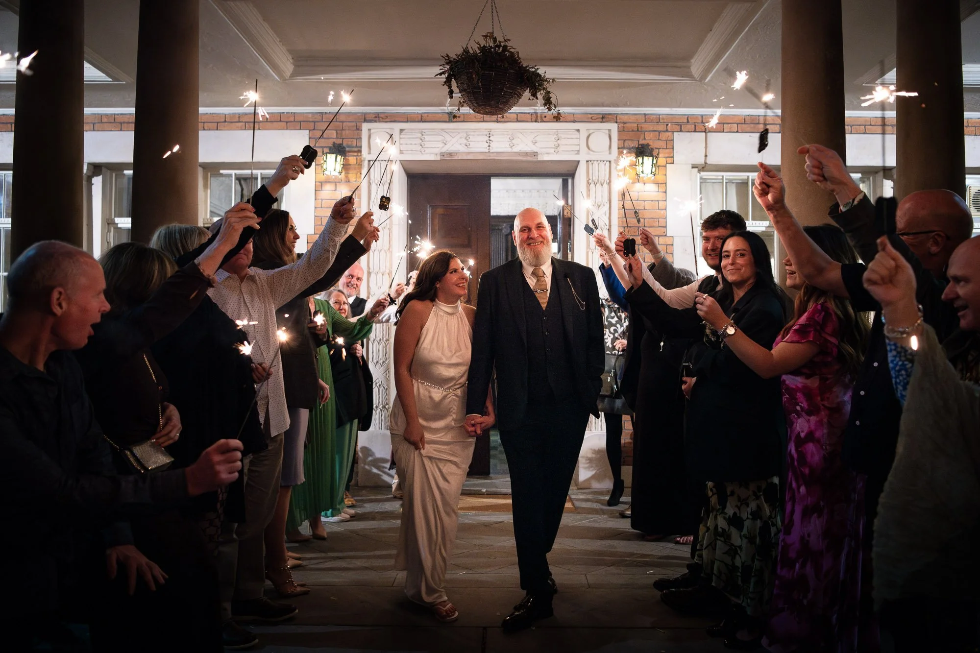Sparklers at a wedding whilst bride and groom walk through a group of their wedding guests