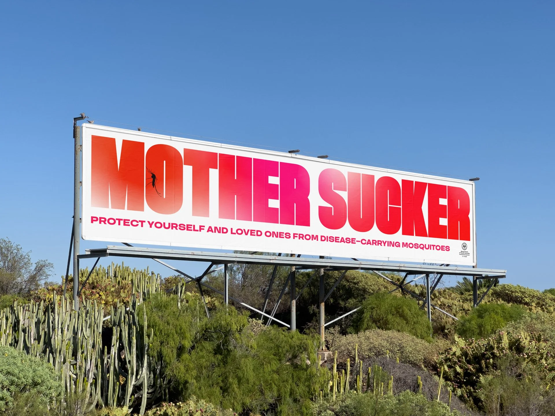 A billboard on a hillside with the text 'MOTHER SUCKER' in large red and pink letters. A smaller caption below reads, 'Protect yourself and loved ones from disease-carrying mosquitoes.' The background shows a clear blue sky and desert-like vegetation