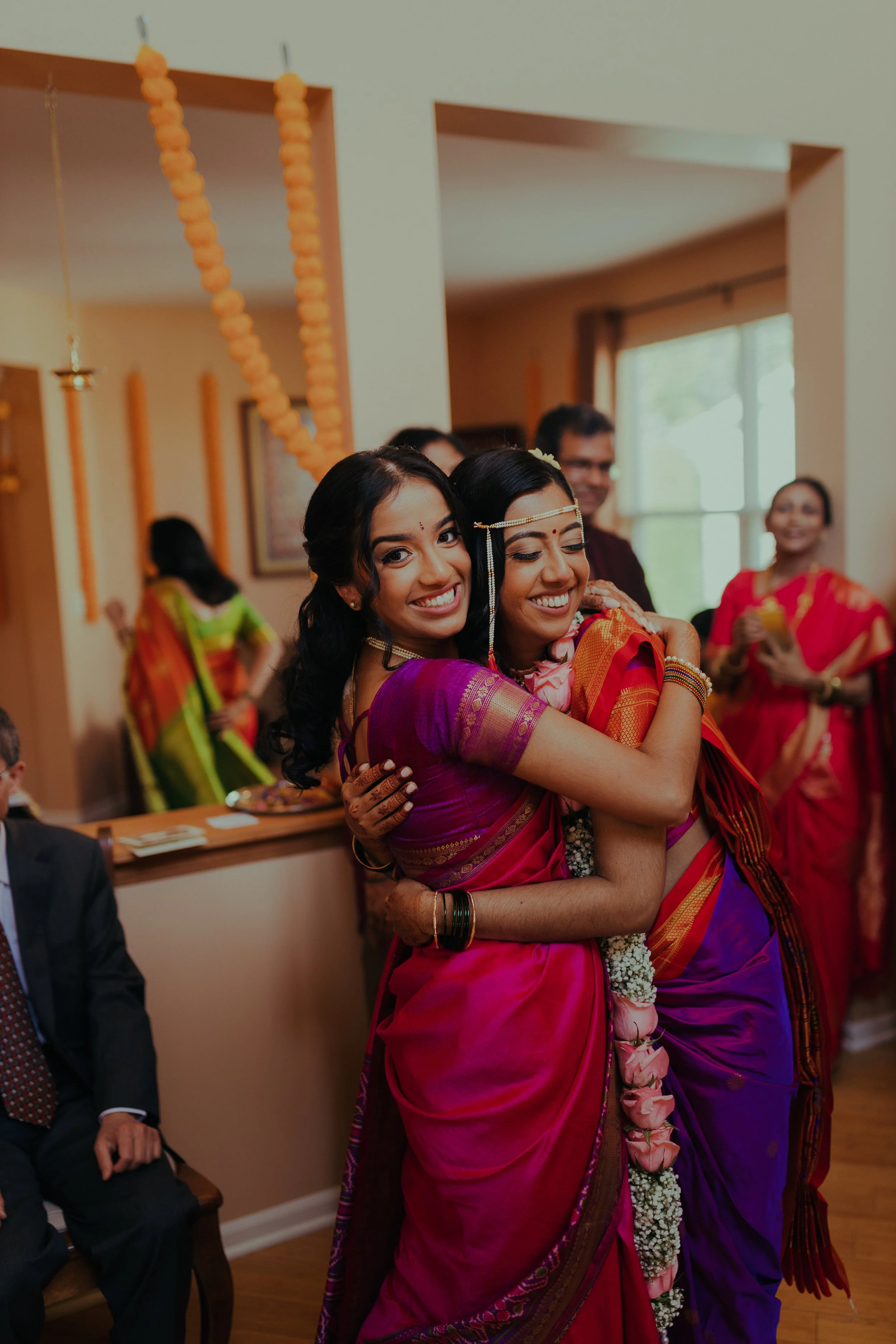 Two women dressed in colorful traditional Indian attire hugging each other and smiling at a wedding celebration. Chicago Indian/Multi-Cultural Wedding Photographer Ttolbphotog