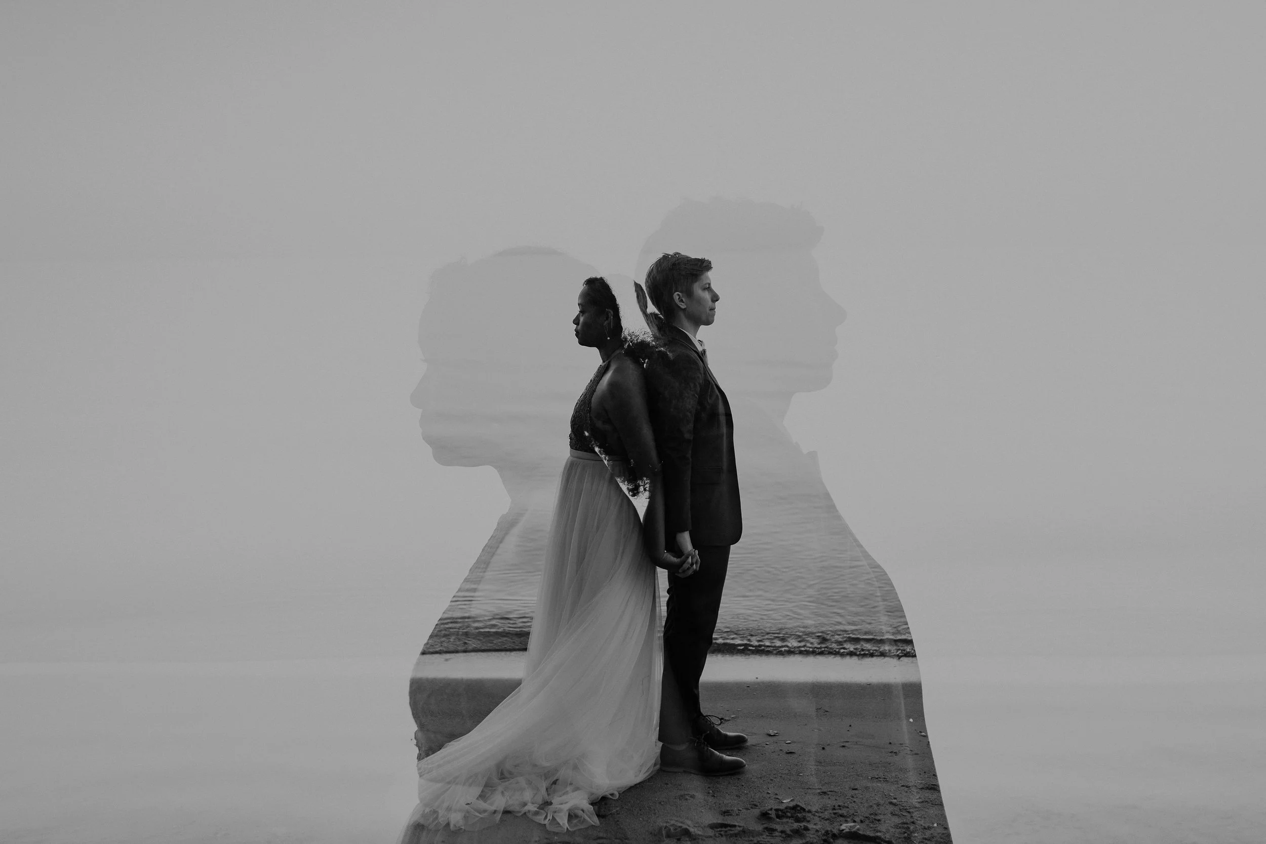 A double exposure image of a couple holding hands on the beach, with their profiles overlapping in black and white, creating a layered portrait.